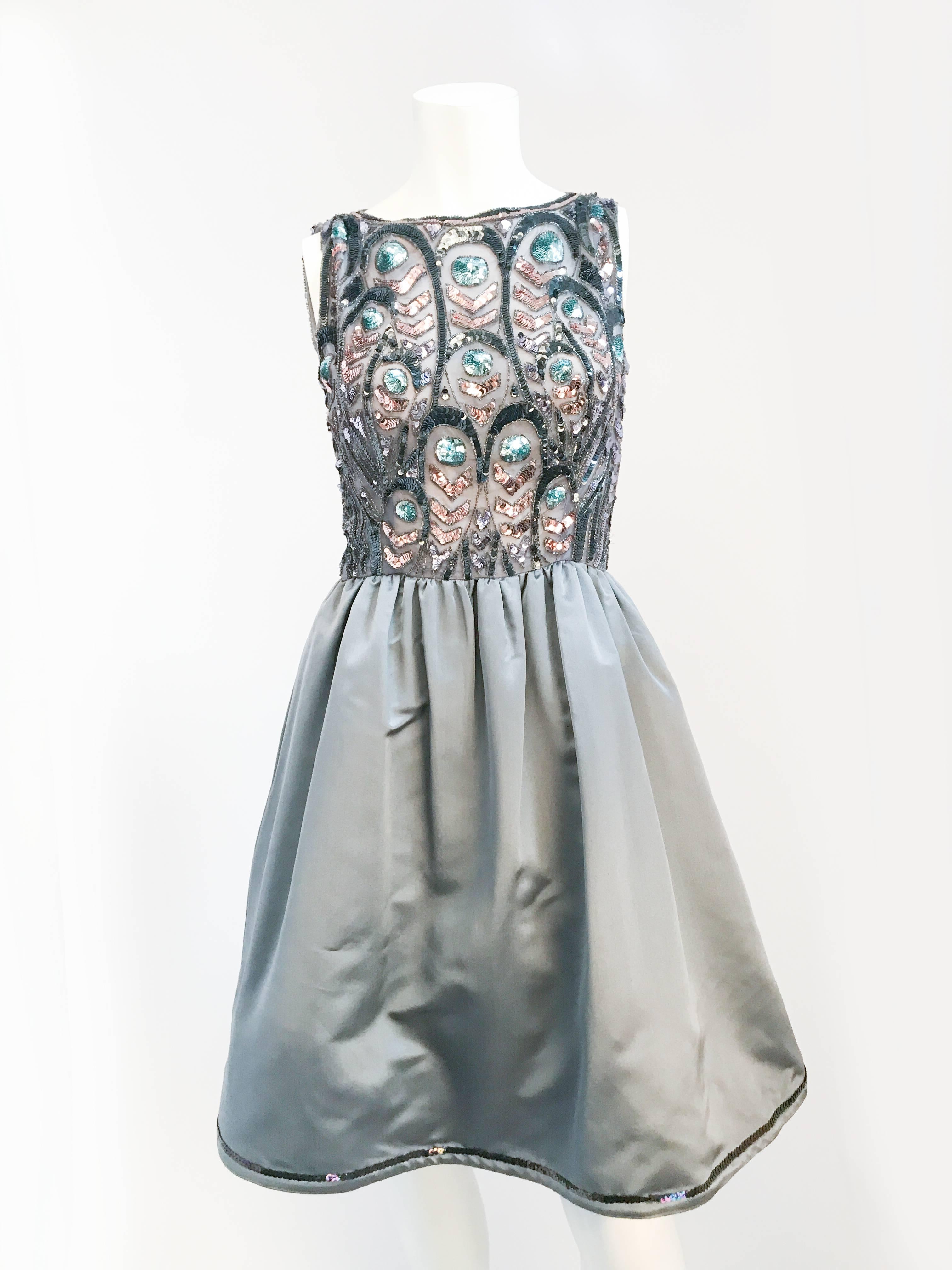 1950s Grey Sequin Cocktail Dress. Grey silk satin sleeveless cocktail dress with multicolored sequin and matching sash. Metal zipper closure located on the back of the dress. 