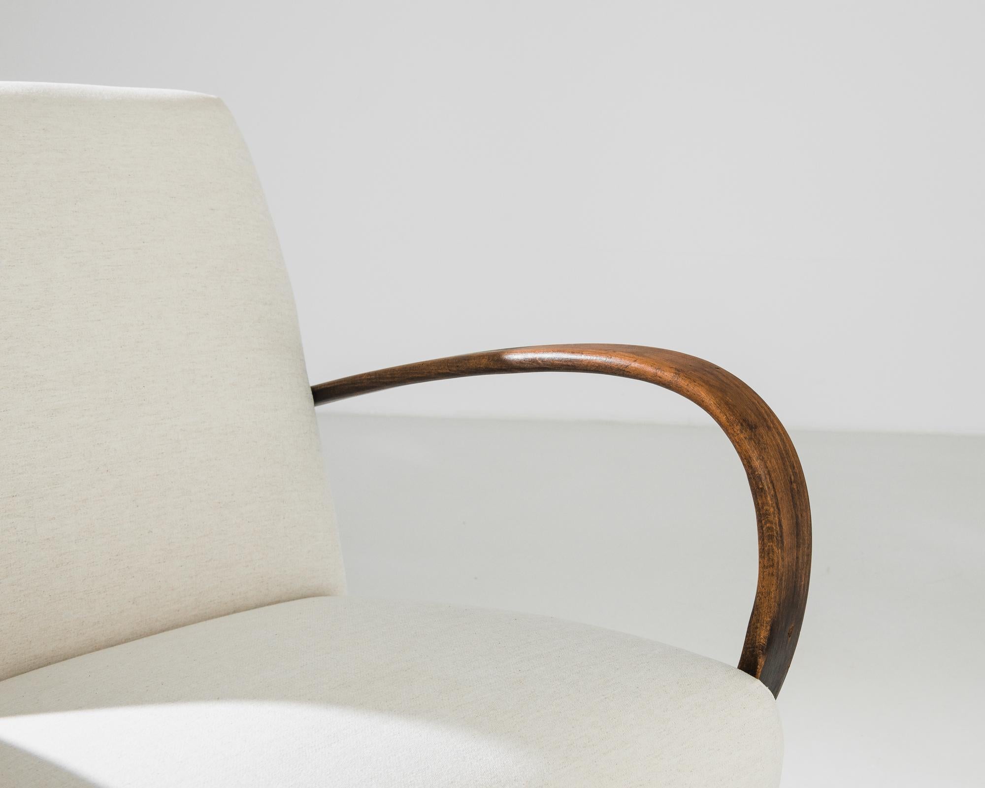 An upholstered armchair by Czech furniture designer J. Halabala. Made in the 1950s, the eye-catching silhouette and comfortable design has an enduring appeal. Influenced by Modern and Art Deco design, a deep upholstered seat upon curved wooden feet