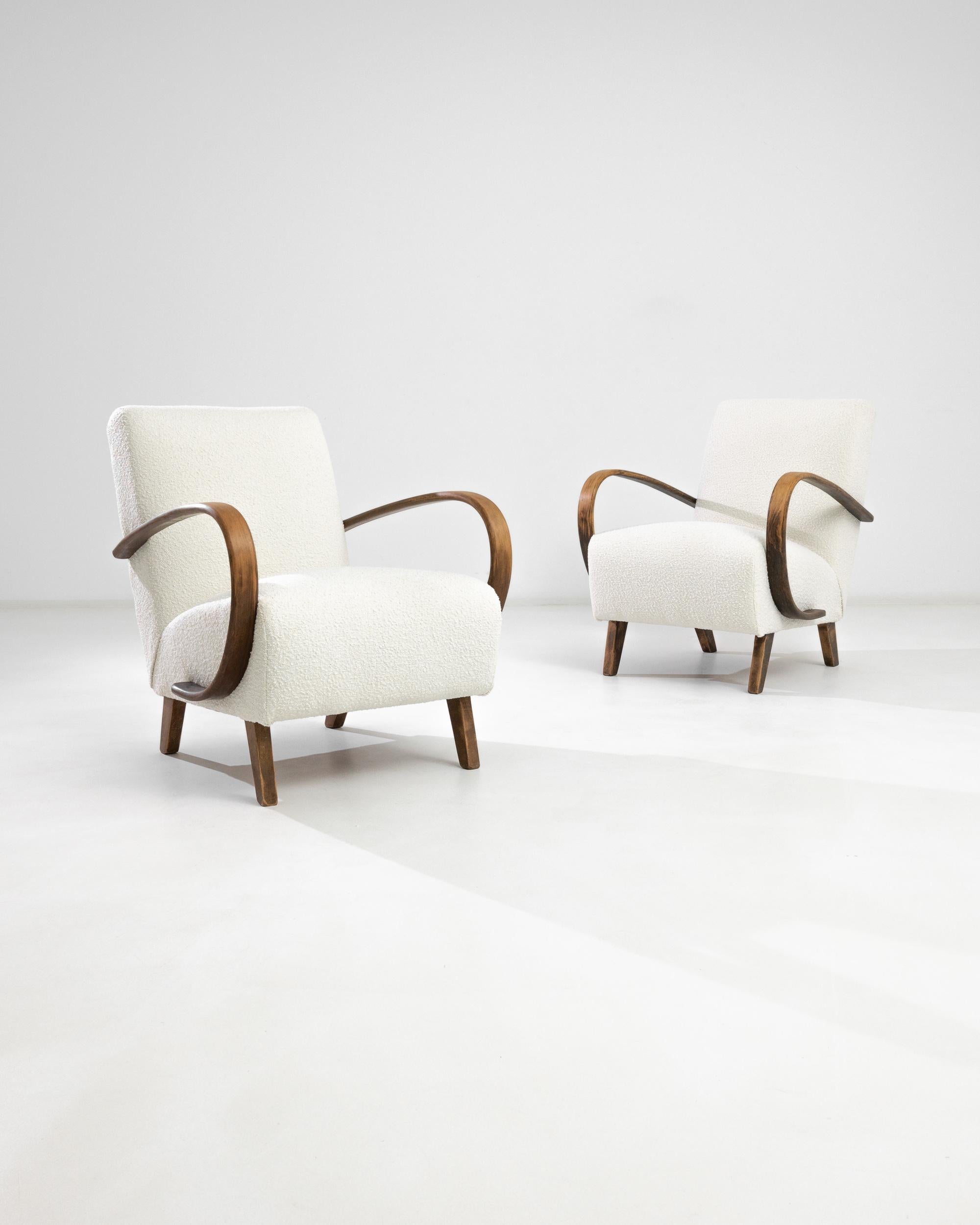 A pair of armchairs by Czech furniture designer J. Halabala. The eye-catching silhouette and comfortable shape has had an enduring appeal. Influenced by Modern and Art Deco design, a deep upholstered seat upon angled wooden feet is framed by the