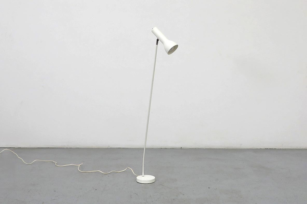 Questa lampada da terra smaltata in bianco è caratterizzata da un elegante paralume allungato, regolabile in base alla posizione e dotato di interruttore on/off, che si collega al sottile stelo con una ferramenta cromata e una base circolare.
