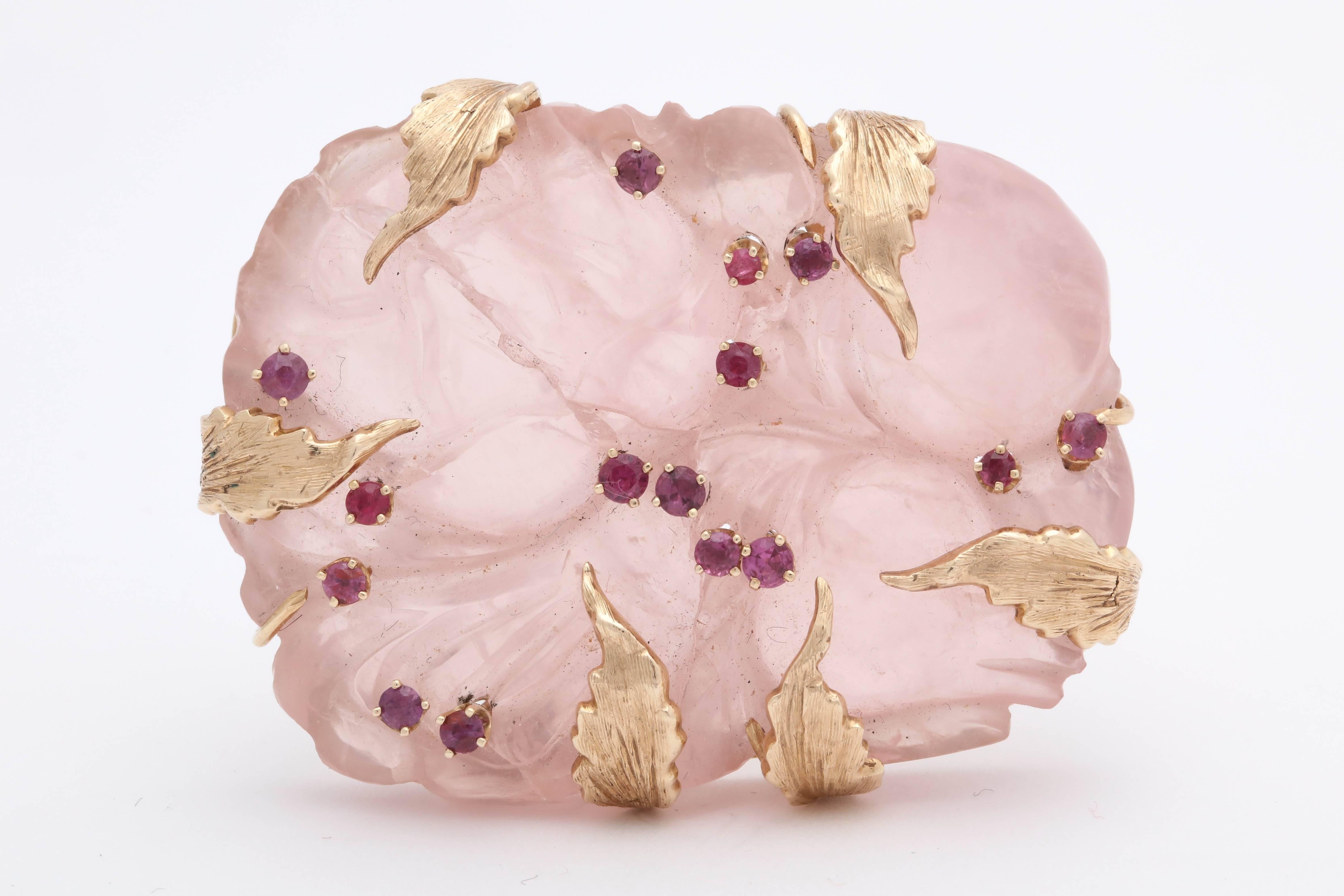 One Ladies 14kt Yellow Gold Brooch Featuring A Large 55Mm Hand Carved Rose Quartz Stone. Brooch Is Embelished With Six Gold Leaf Pieces Within The Design Of The Rose Quartz.Brooch Is Also Embellished with 15 Faceted Rubies Weighing approximately