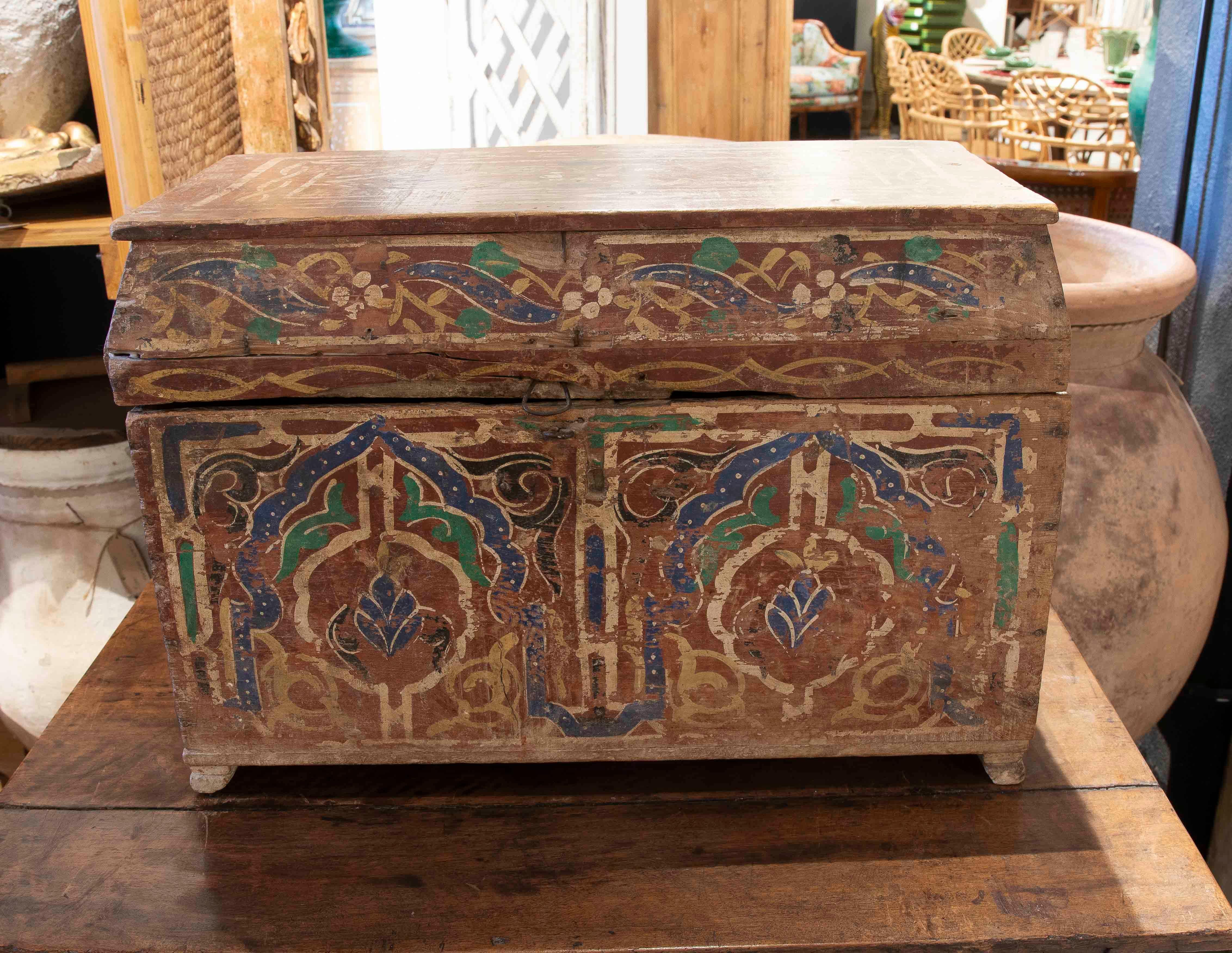 Magnifique coffre en bois à la riche patine ancienne, décoré de motifs géométriques et floraux mauresques peints à la main dans des tons de bleu, de vert et d'or. Son design évoque des influences orientales ou mauresques, reflétant un artisanat