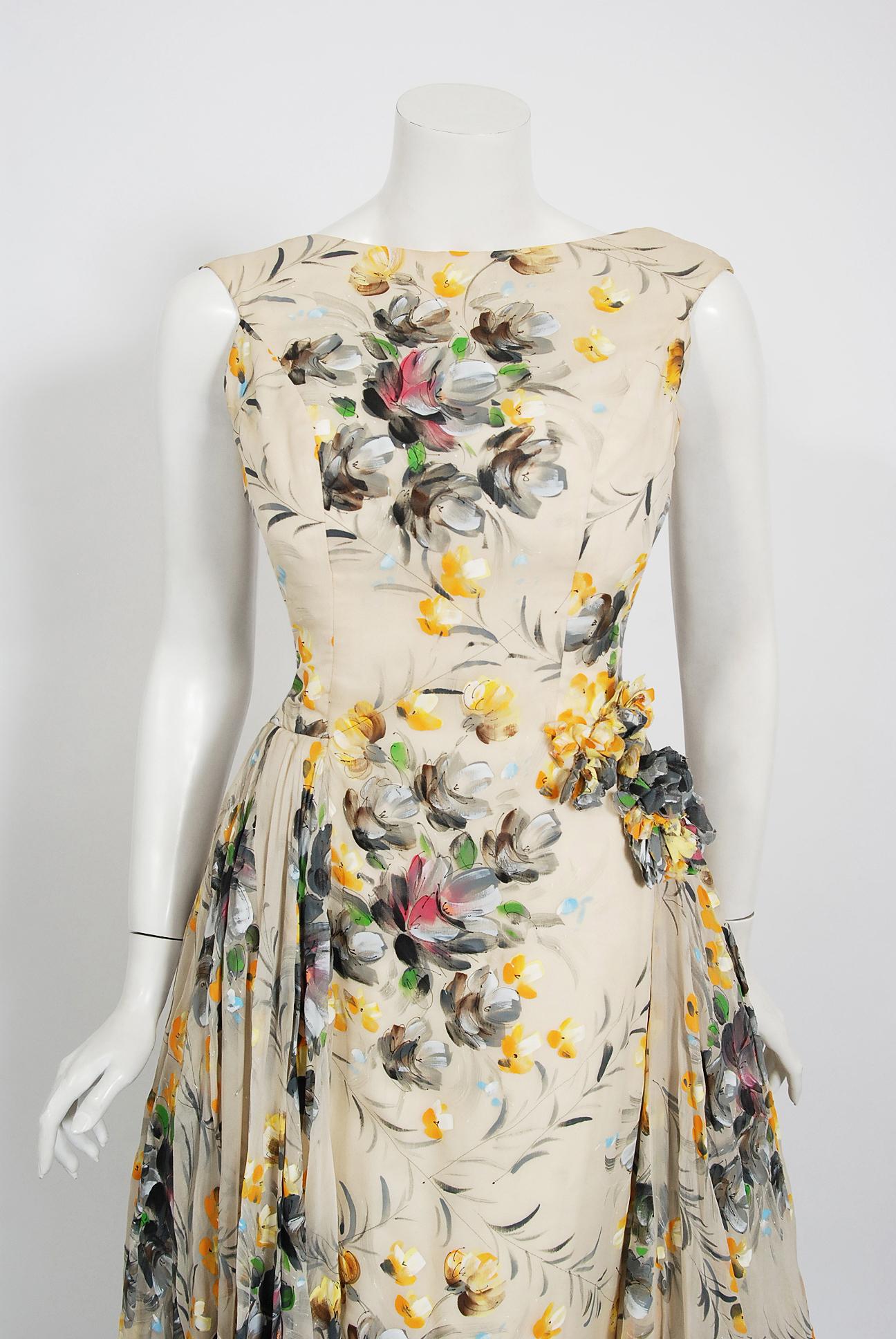 In this gorgeous 1950's hand-painted colorful floral gown, the detailed construction and meticulous attention to detail are comparable to what you will find in modern couture. This captivating garment is fashioned from double layered silk organza in