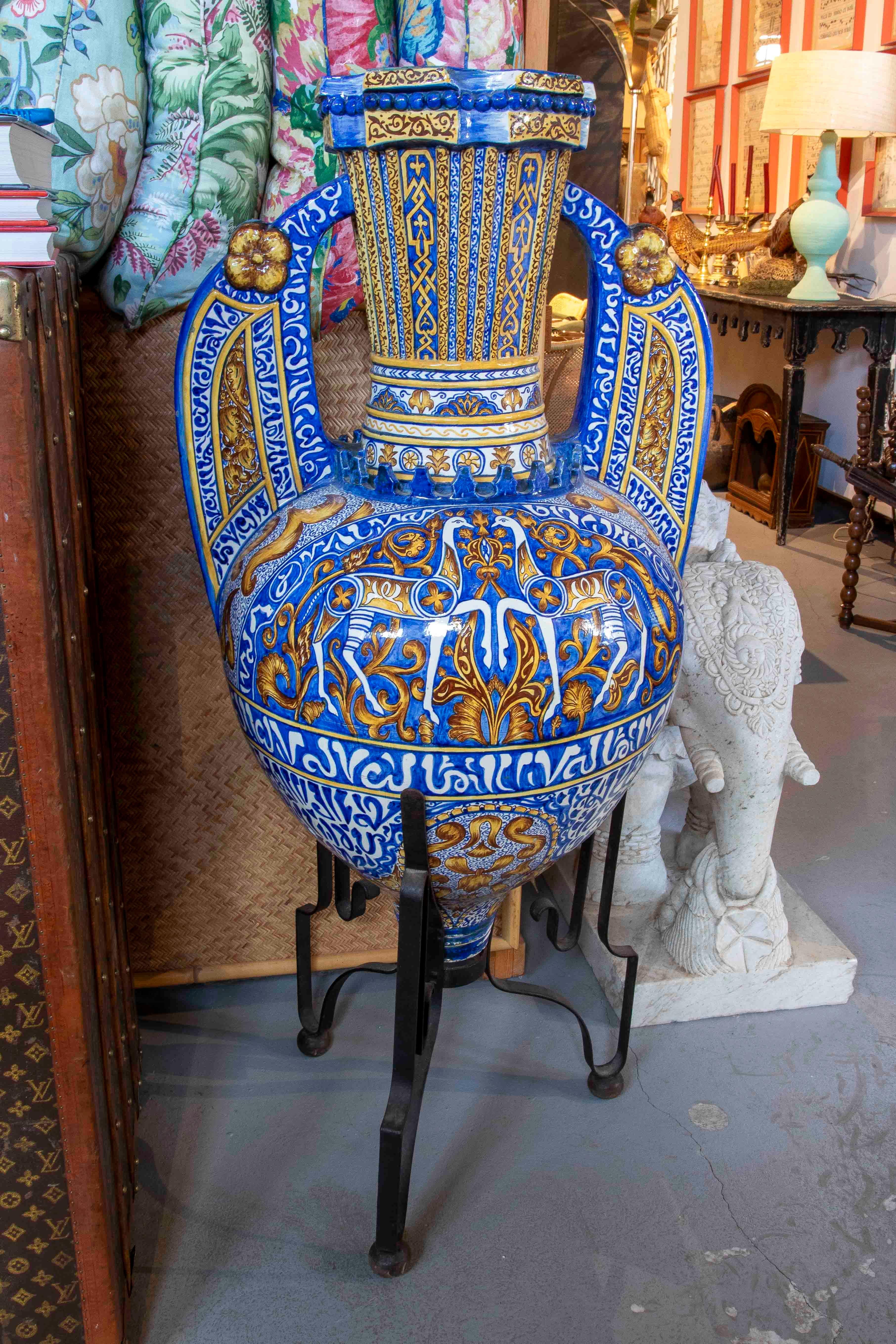 Magnifique amphore espagnole de grande taille, en céramique émaillée, richement décorée à la main de motifs de la Renaissance en bleu de cobalt, or et blanc.

Le corps globulaire est orné d'arabesques, de rinceaux et de boucliers stylisés, tandis