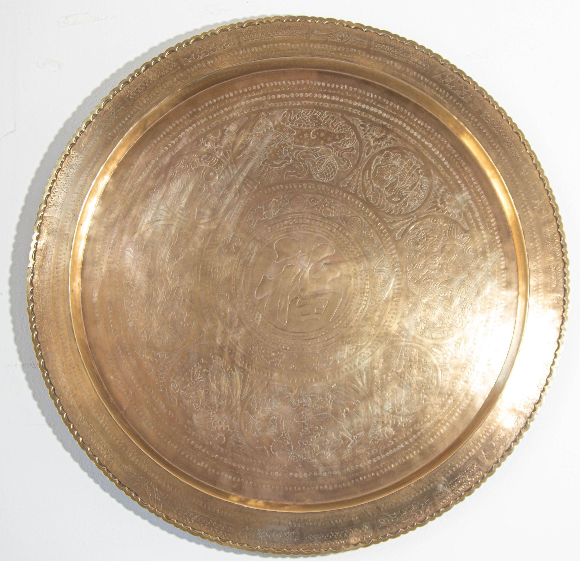 Large vintage Asian handcrafted round tray with a patina from the 1950s.
The tray features a hanging hook, allowing it to be displayed on a wall or placed flat as a centerpiece on a table.
Its surface is adorned with intricate oriental symbols,