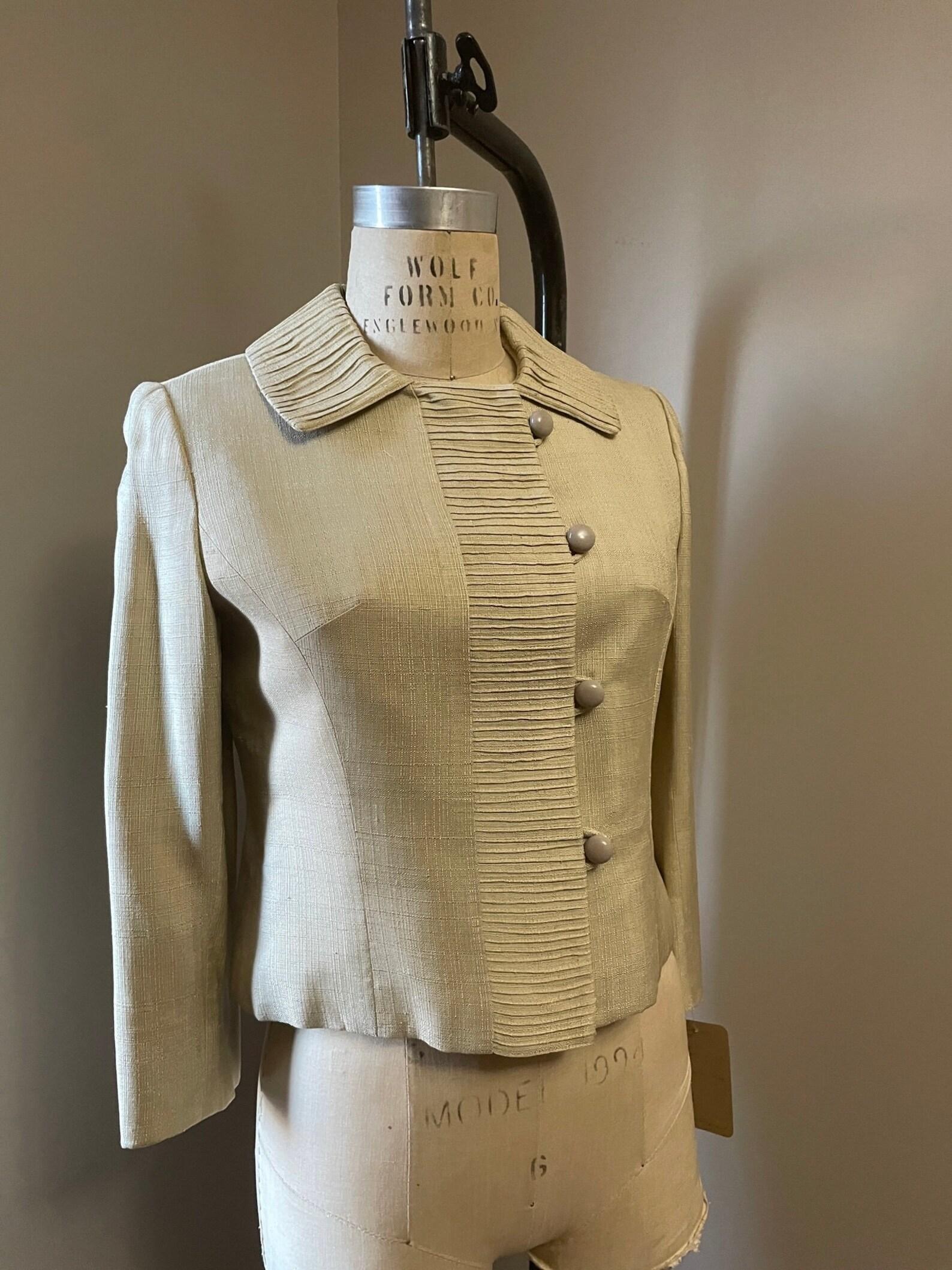 Vintage Hannah Troy ecru beige blazer. flat pointed collar. bust darts. long sleeves. beautiful pleating at collar & placket. cropped body. silk lining. the jacket is weighted at 4 different points along the interior hem. beautifully constructed
