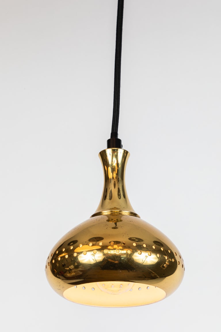 1950s Hans-Agne Jakobsson perforated brass pendants for Markaryd, Sweden. Graced with simple Scandinavian curves and pleasing brass patina. Professionally rewired for US electrical. Height is readily adjustable to desired length. Original