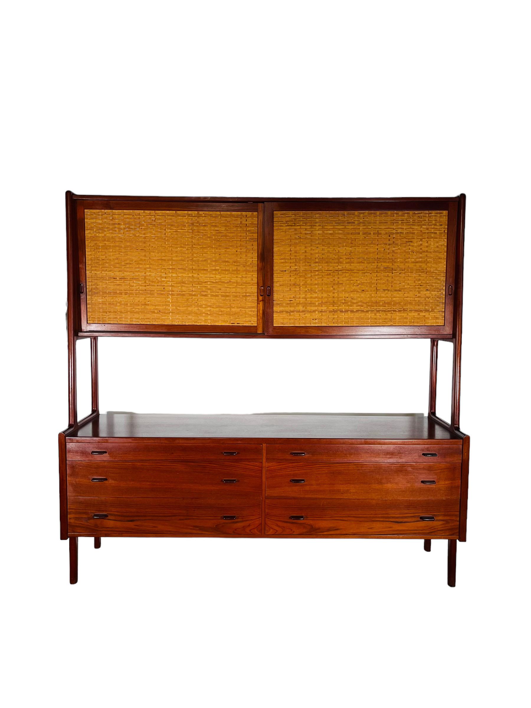 This stunning Hans J. Wegner Danish teak credenza is the perfect addition to any modern home. Crafted from solid teak wood, this credenza features a sleek, mid-century modern design with two wicker sliding doors and six drawers for ample storage.