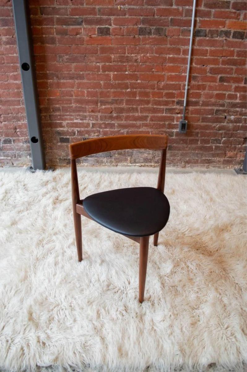 Introducing this 1950s Hans Olsen for Frem Røjle sculpted teak dining chair, featuring the iconic three-legged design. It boasts a gently curved back and a contoured seat freshly upholstered in black Edelman leather, supported by three tapered teak