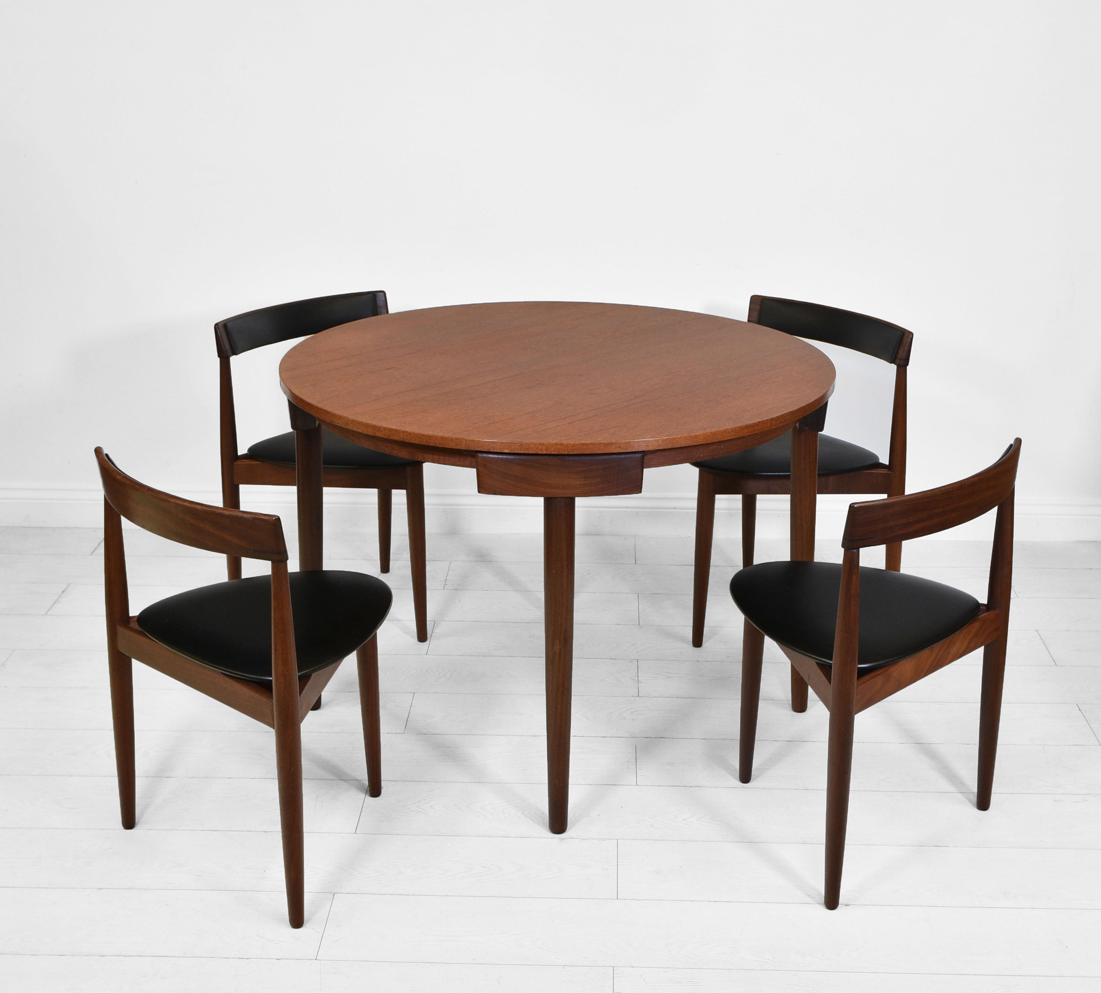 A Danish compact circular teak dining set designed by Hans Olsen for Frem Rojle. Maker's stamps. Circa 1950s.

The set consists of a round dining table and four dining chairs in a three leg design, with the original black vinyl seating.

Very