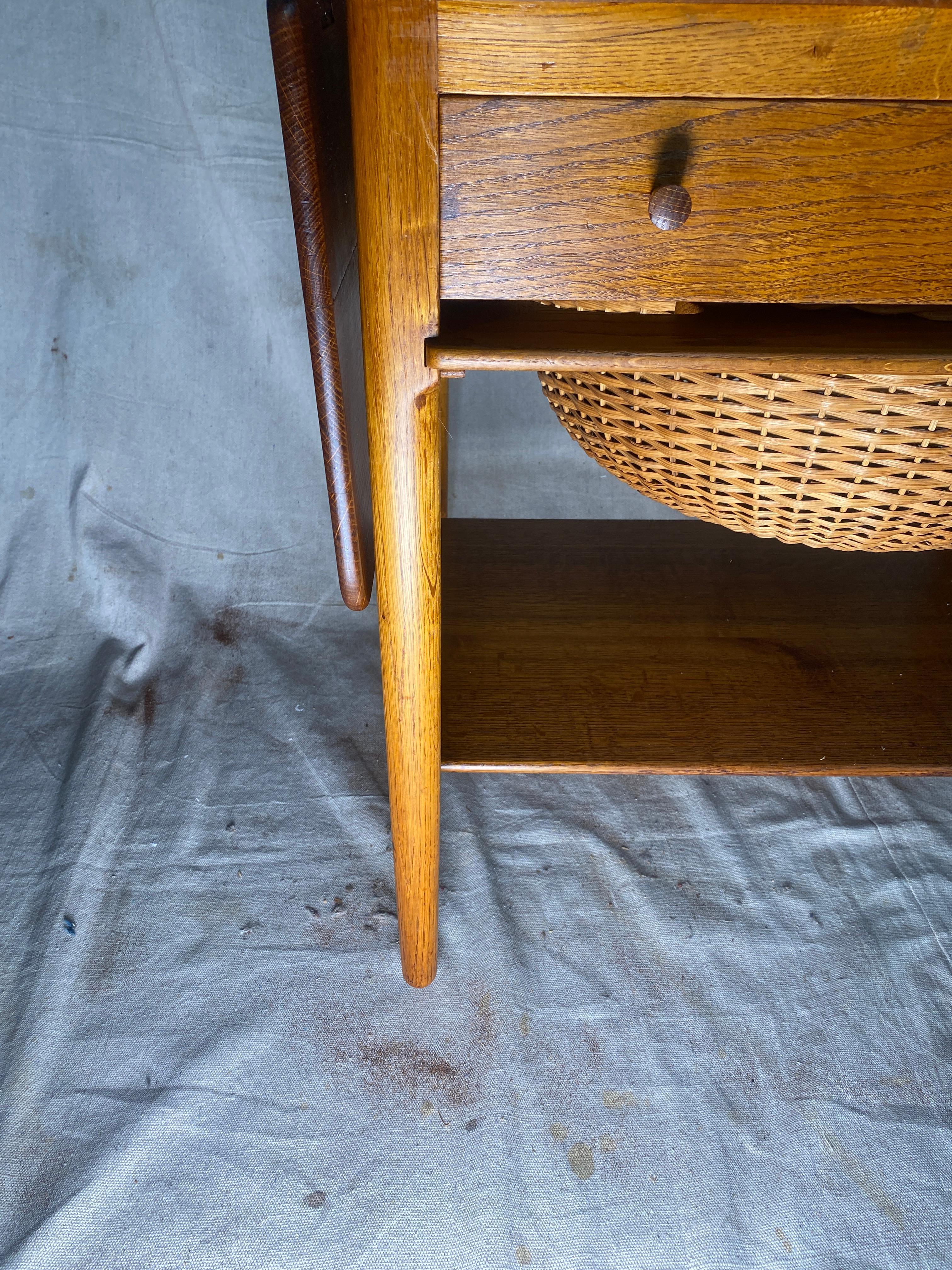 Magnifique exemple de table de couture AT-33 conçue par Hans Wegner et fabriquée au Danemark par l'ébéniste Andreas Tuck. Cette table en teck et en chêne est dotée de deux allonges, d'un tiroir avec compartiments pour le matériel de couture, d'un