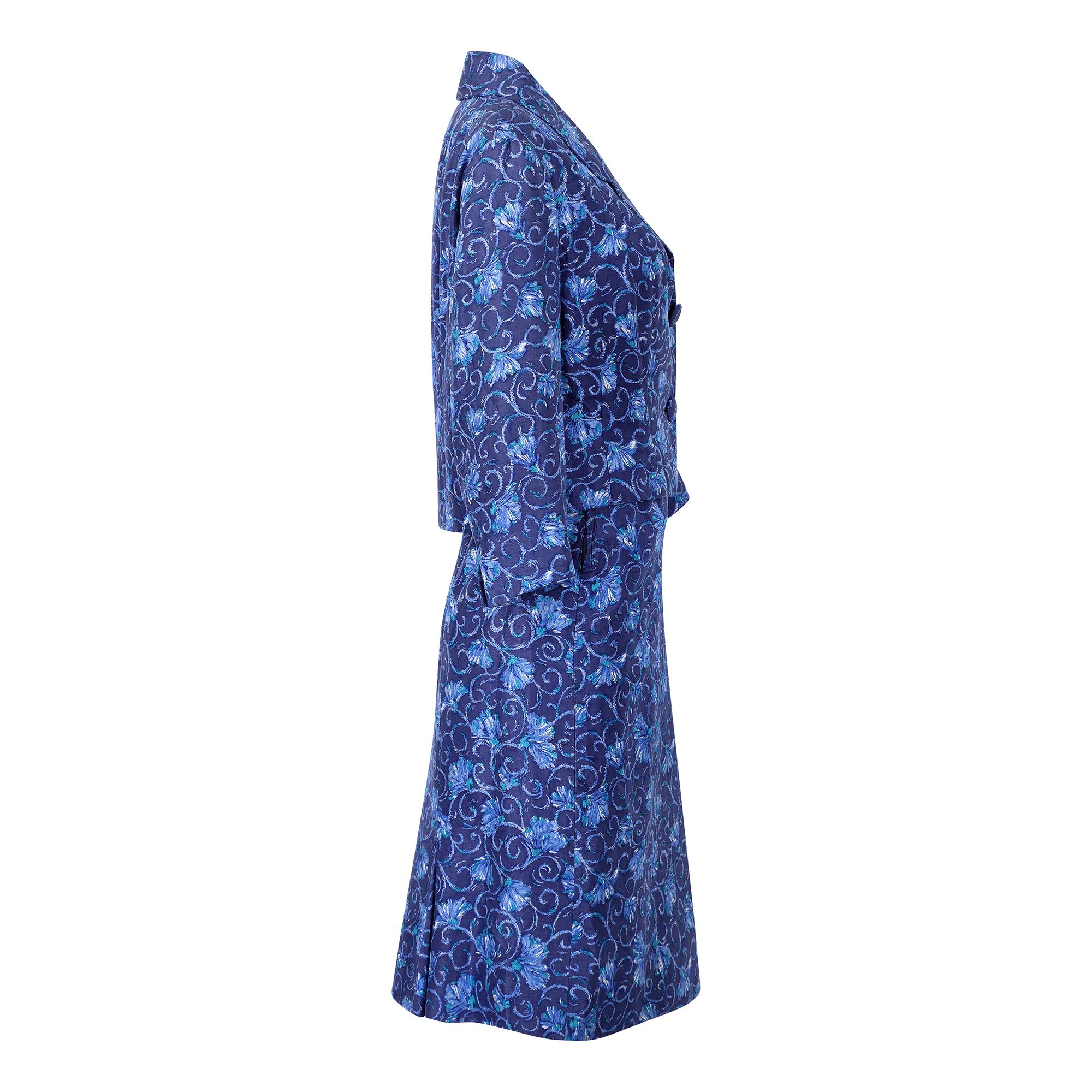 Ce tailleur-jupe original en soie des années 1950 est signé du couturier royal Hardy Amies, l'un des noms les plus connus de la mode mondaine britannique des années 50 et 60. D'un magnifique bleu vif, le tissu présente un motif floral défilant