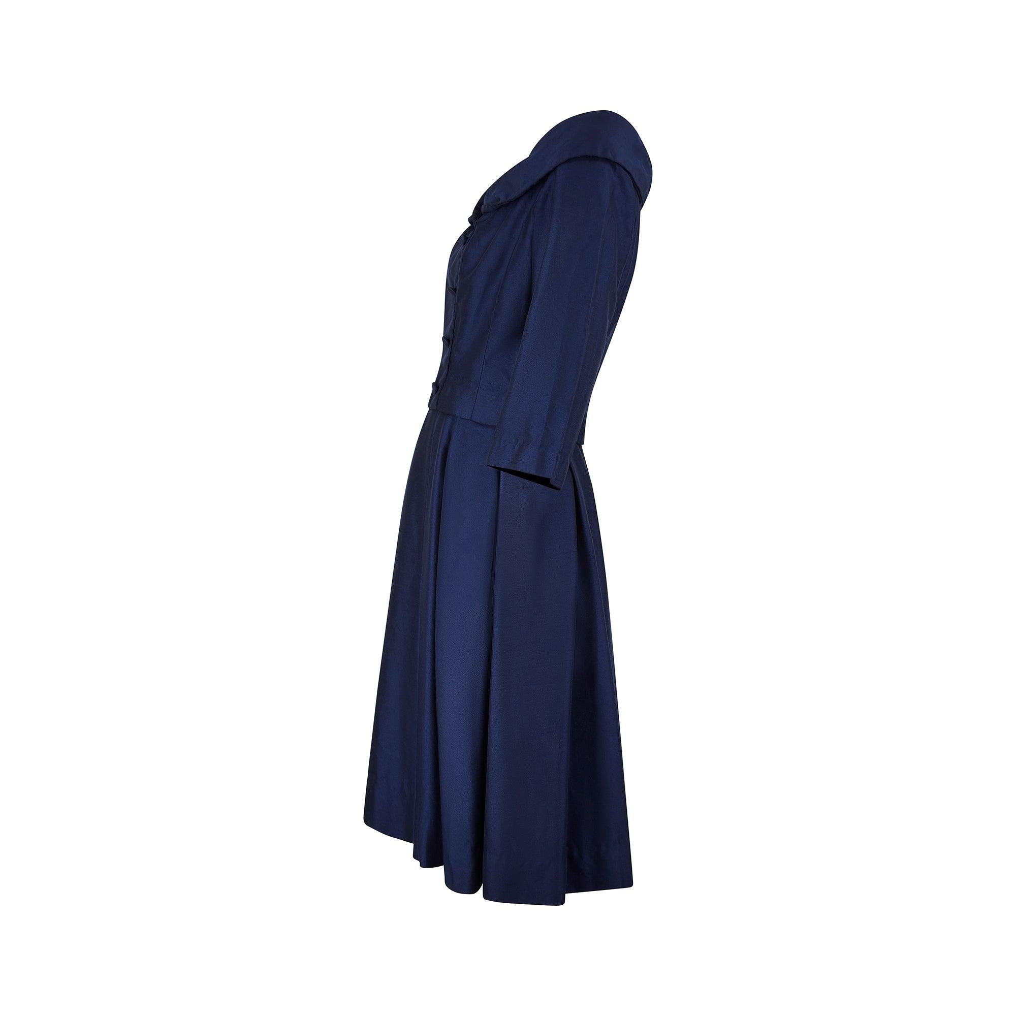 This dress is the epitome of elegance. Designed for iconic London department store Harrods in the late 1950s, it gives the illusion of a two-piece suit made up of a double-breasted jacket and skirt but is, in fact, a midi-dress. The wide neckline