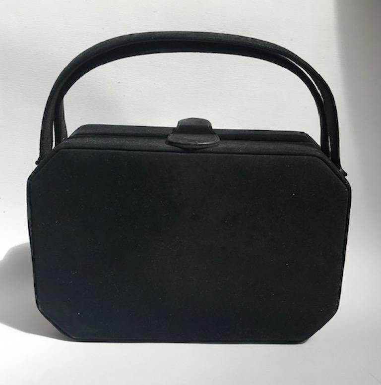A stunning and rare box hand bag by Harry Rosenfeld from the late 1940s to 1950s. The exterior is black suede with a midnight blue satin interior. In the center front of the bag is a 3 inch wide by 2 inch high frame. The gilt frame is intricately