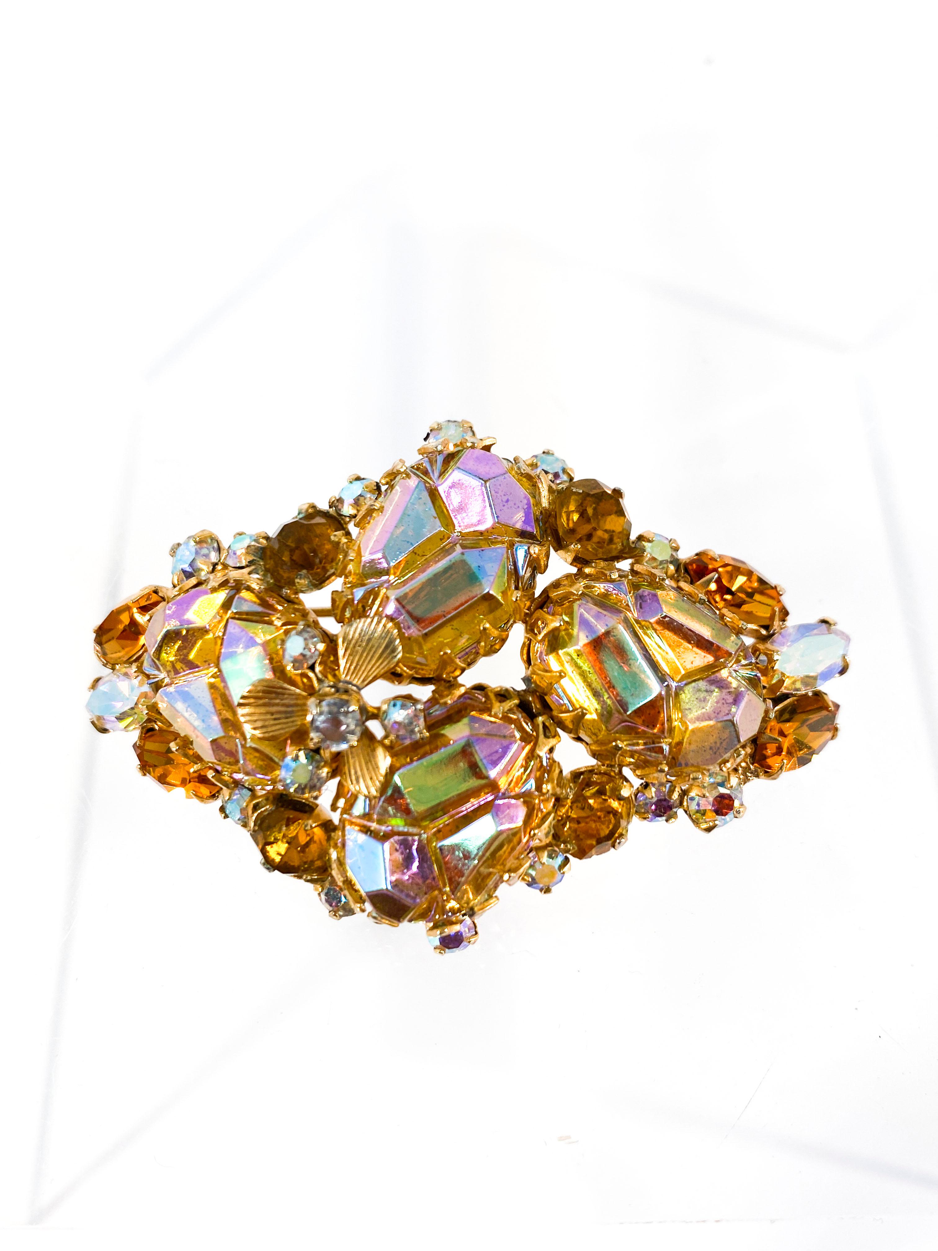 1950s Hattie Carnegie brooch featuring iridescent and multi-toned rhinestones in several different cuts. The stones are accented with etched leaves in brass.
