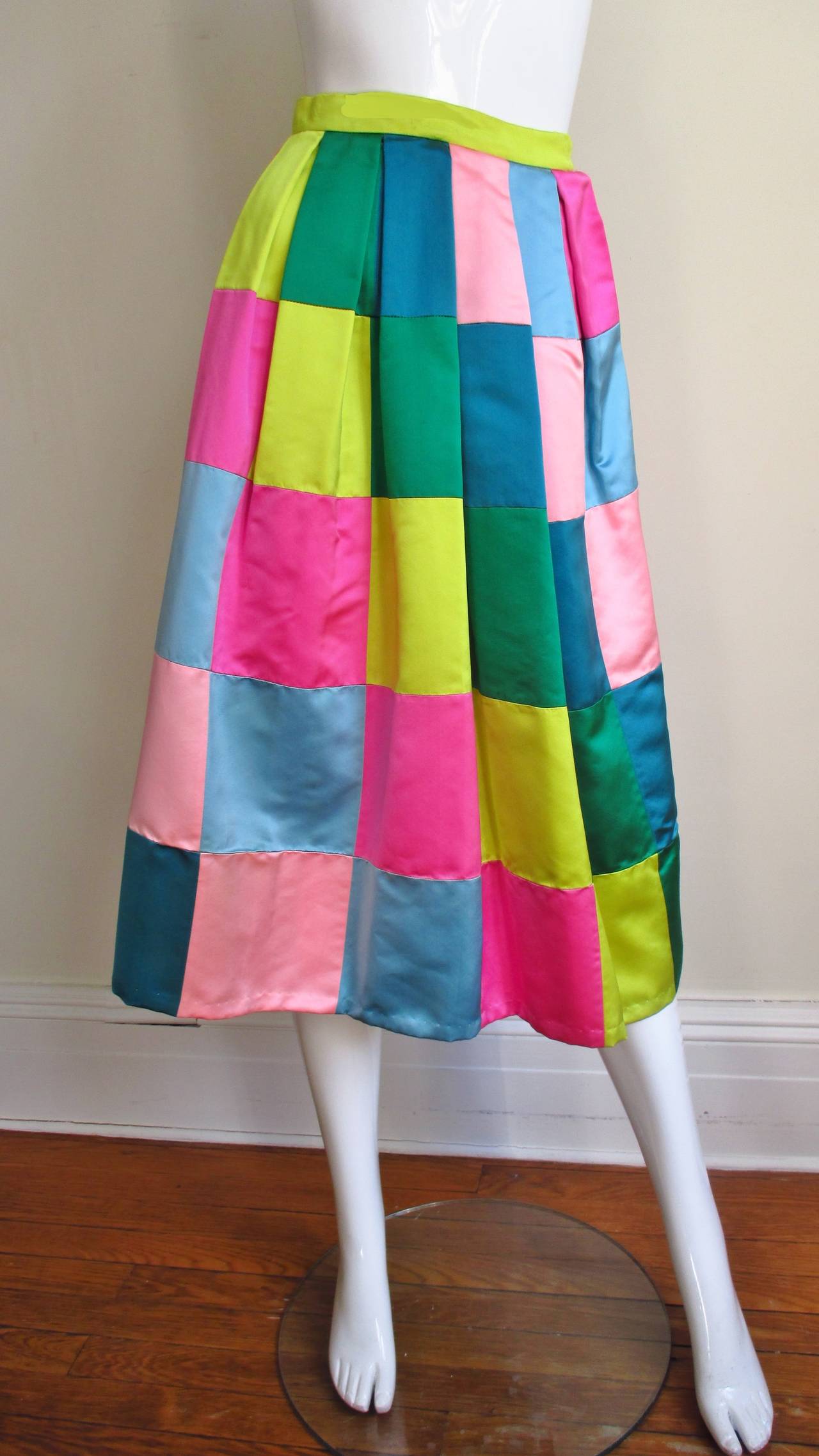 A colorful silk patchwork skirt in greens, blues, and pinks. The skirt is comprised of  row of squares sewn creating a diagonal pattern of same colors. It has a small waistband, a hand sewn side zipper, and is lined in off white silk. 
Fits size