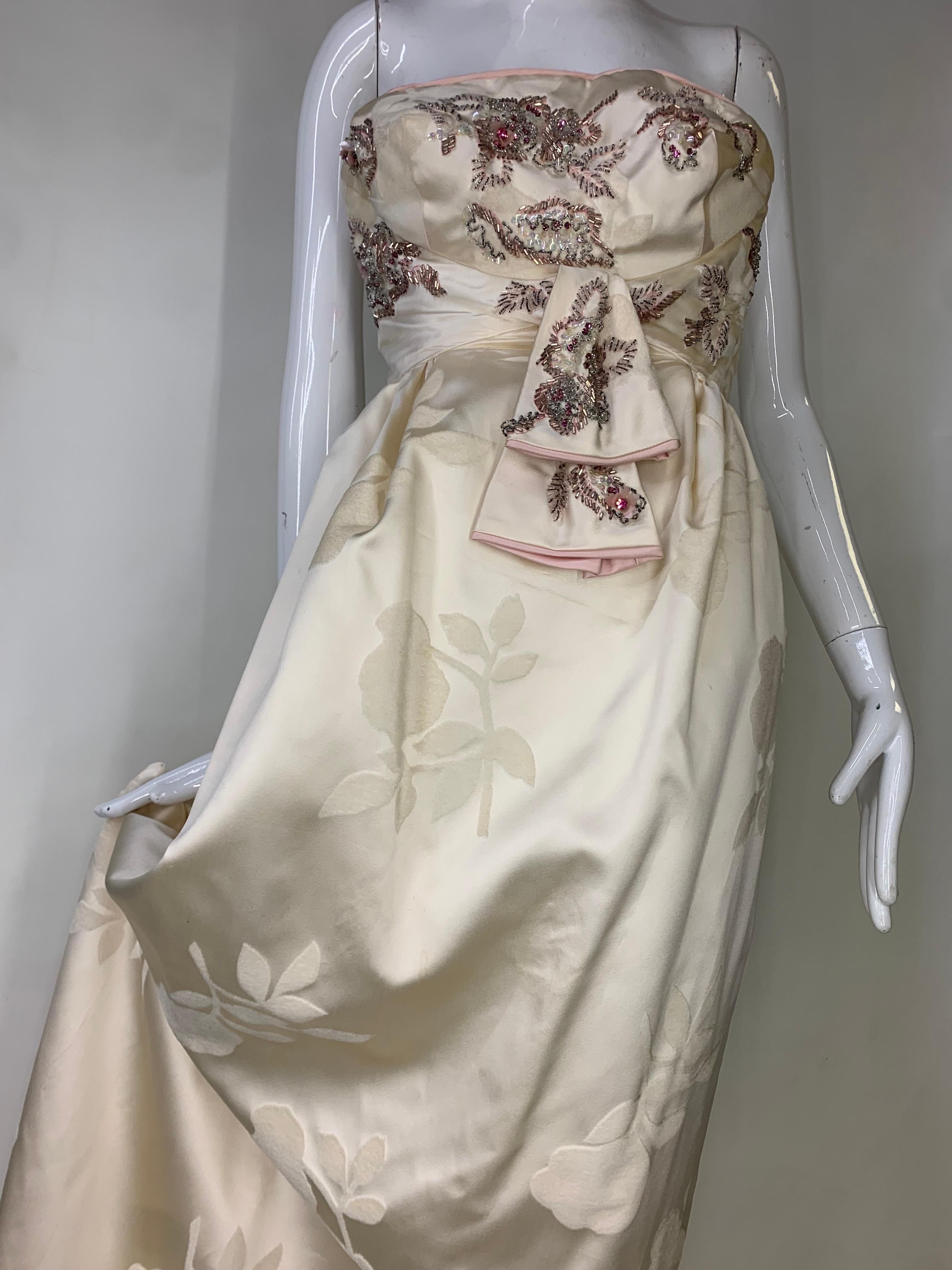 1950s Helena Barbieri Original Cream Silk Flocked Beaded Strapless Gown: A sensual original design features a floral motif beaded and jeweled bodice in a subtle and appealing style accented with pink piping. Sash front waist. Simple gathered skirt