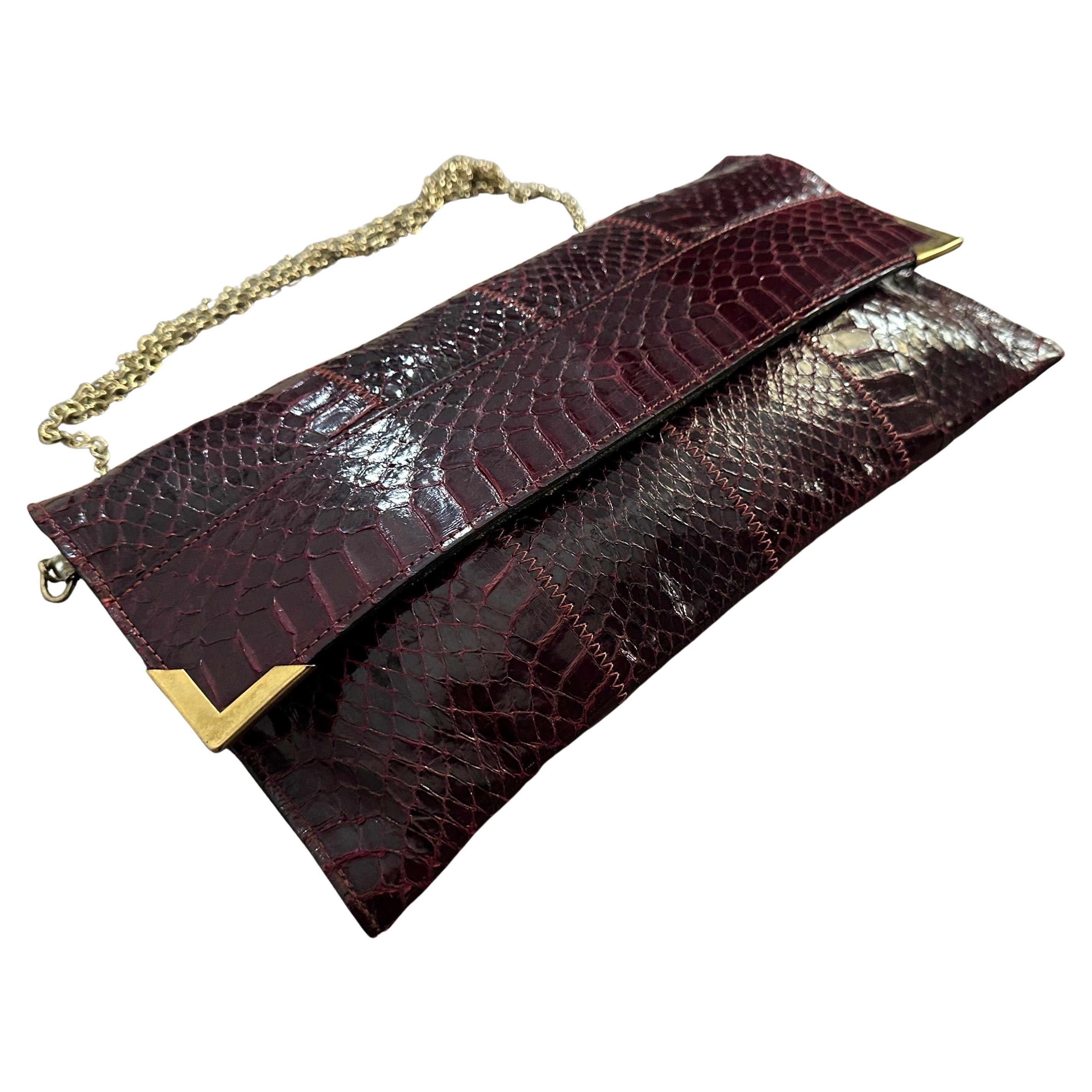 This exquisite 1950s Italian shoulder bag is a testament to timeless elegance and expert craftsmanship. Made from high-quality burgundy leather with a luxurious snakeskin texture, the bag features a sleek, structured design that exudes vintage