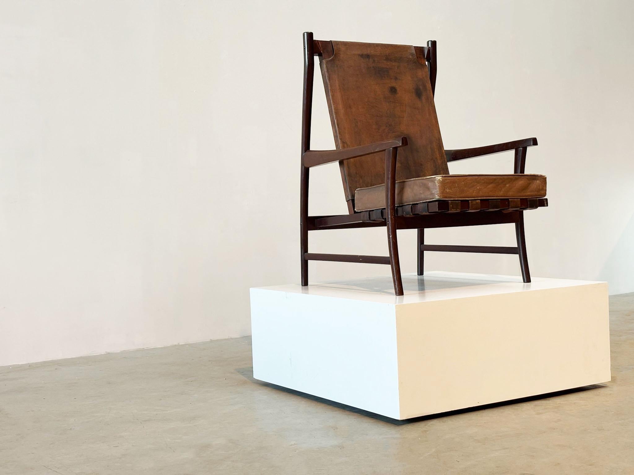 Chaise longue brésilienne des années 1950
Cette chaise brésilienne des années 1950 présente un dossier haut et est fabriquée en bois tropical. Il possède encore le cuir marron d'origine, préservé pour conserver sa patine naturelle. Le coussin a été
