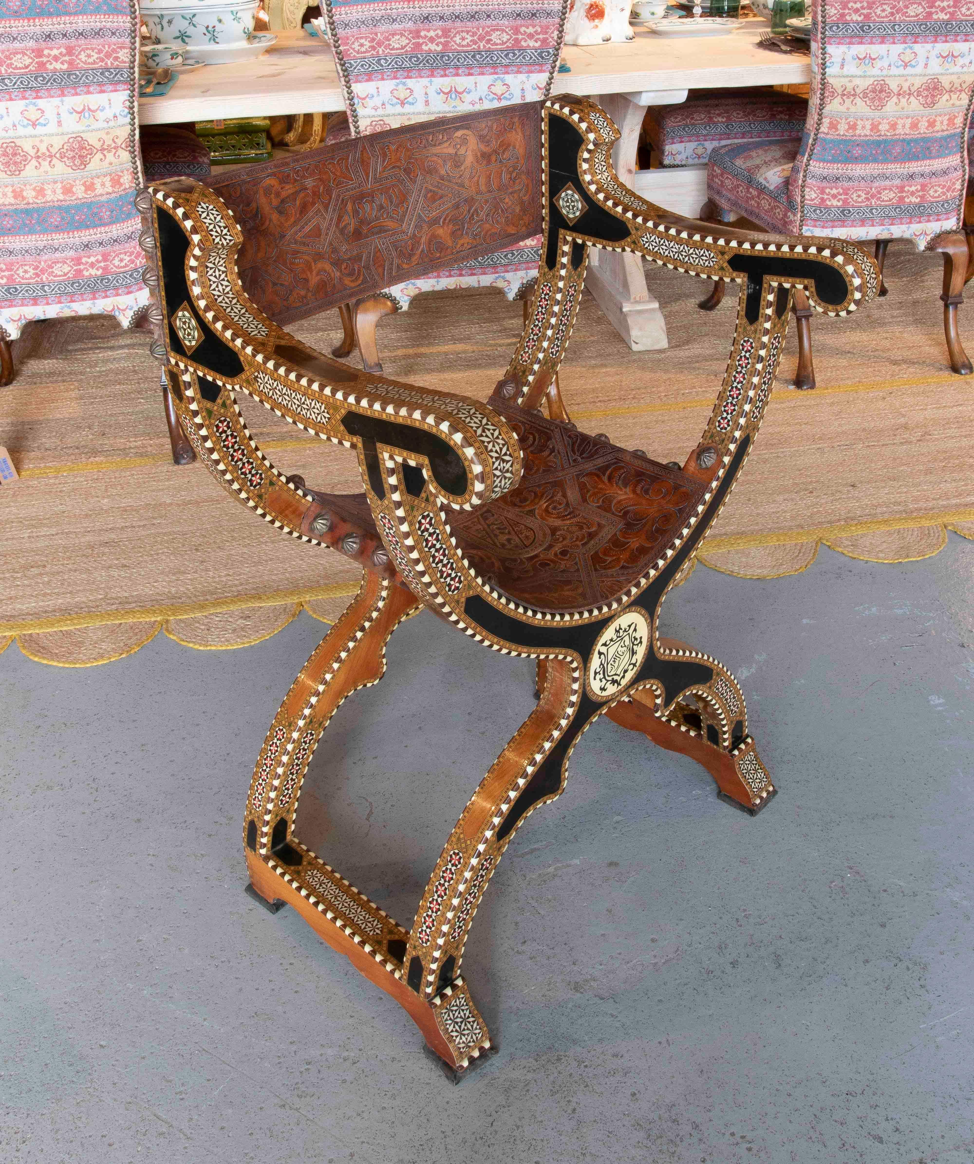 Exceptionnelle chaise de style Curule, fabriquée en bois finement ouvragé et décorée d'incrustations de nacre et d'os dans des motifs géométriques complexes. L'assise et le dossier sont fabriqués en cuir gaufré avec des motifs d'arabesques, ce qui