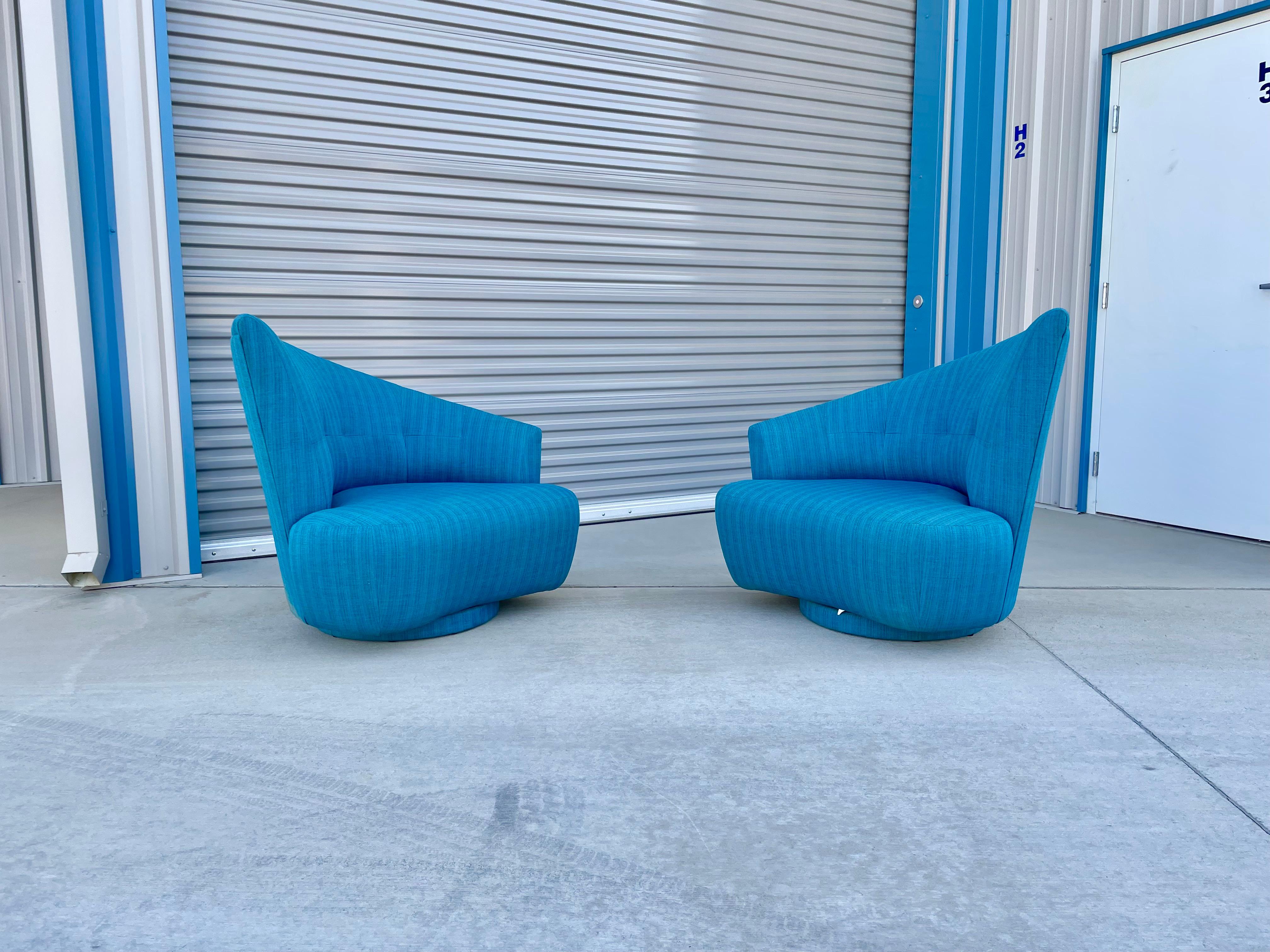 Beautiful pair of Hollywood regency asymmetrical swivel chairs manufactured and designed in the United States, circa 1950s. This pair of lounge chairs feature a unique curved backrest, which offers solid support and comfort for your back. The chairs