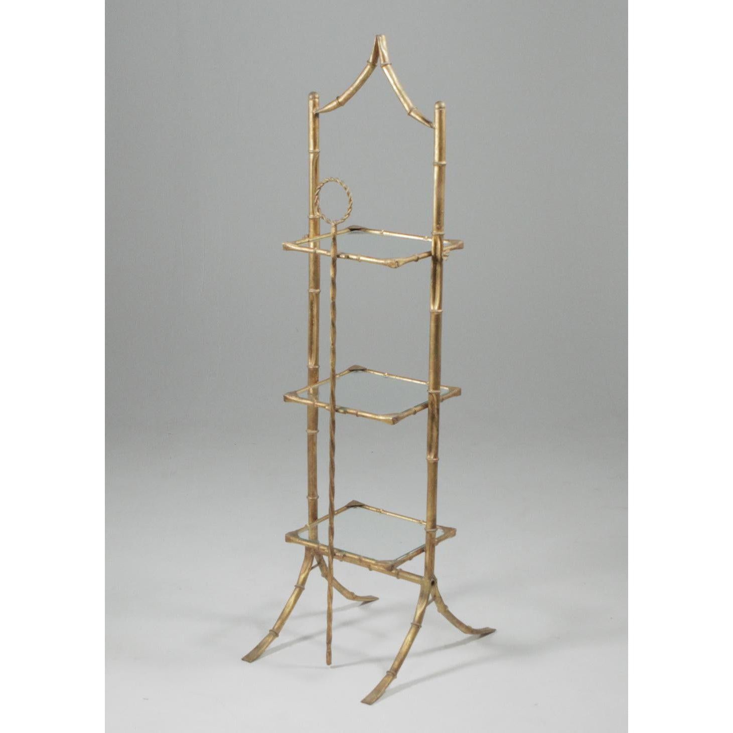 A Hollywood Regency three tier faux bamboo étagère or cake Stand in the style of Maison Baguès. Unmarked, Italian from the 1950s. The shelves collapse for storage. The glass shelves are original, and cannot be removed. The vertical bar in the back