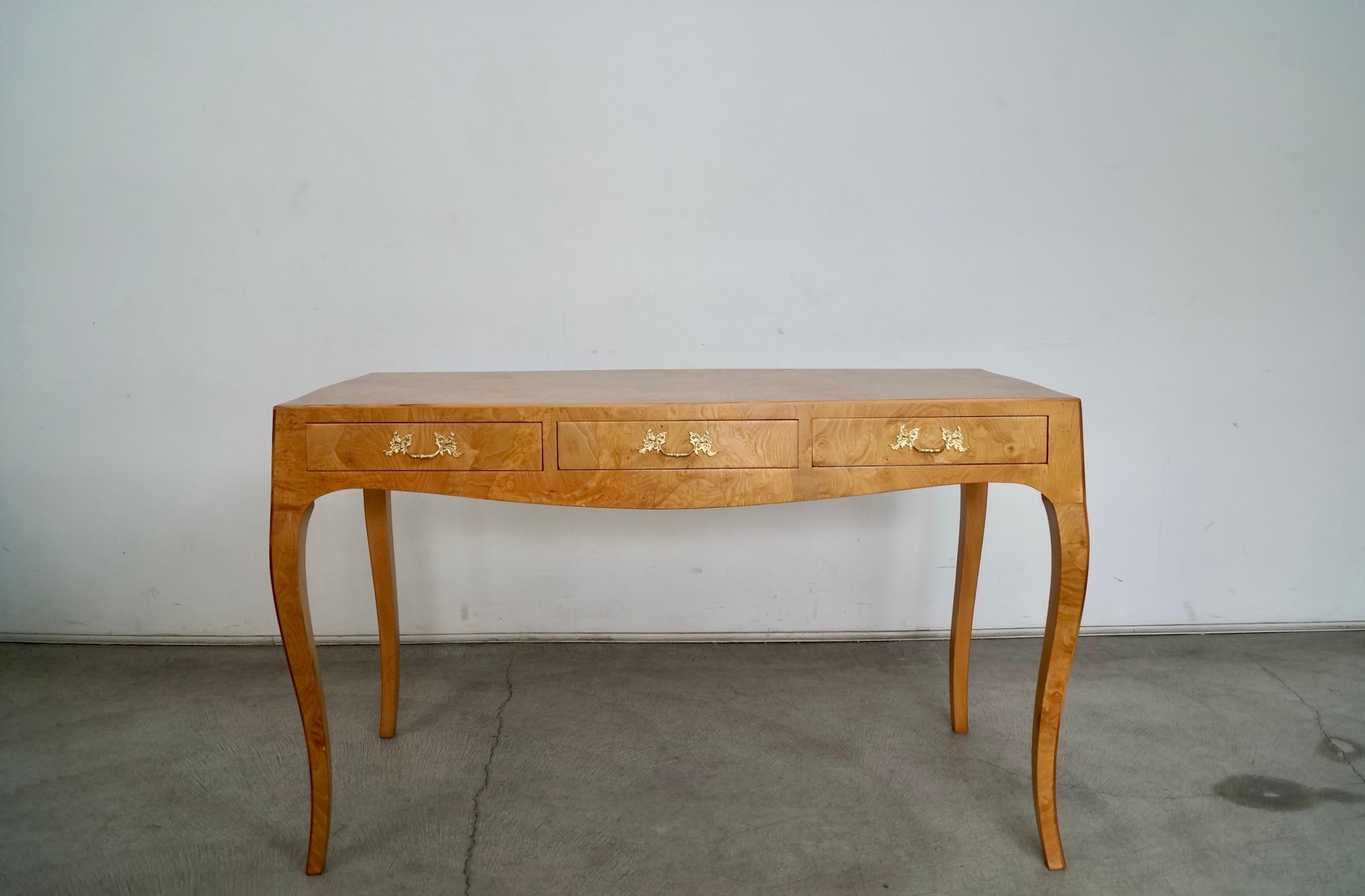 Vintage 1950's Hollywood Regency desk or console table for sale. Made in Italy in the 1950's, and has beautiful burlwood patchwork with saber legs. It has three drawers with the original solid brass hardware. It has been professionally refinished in