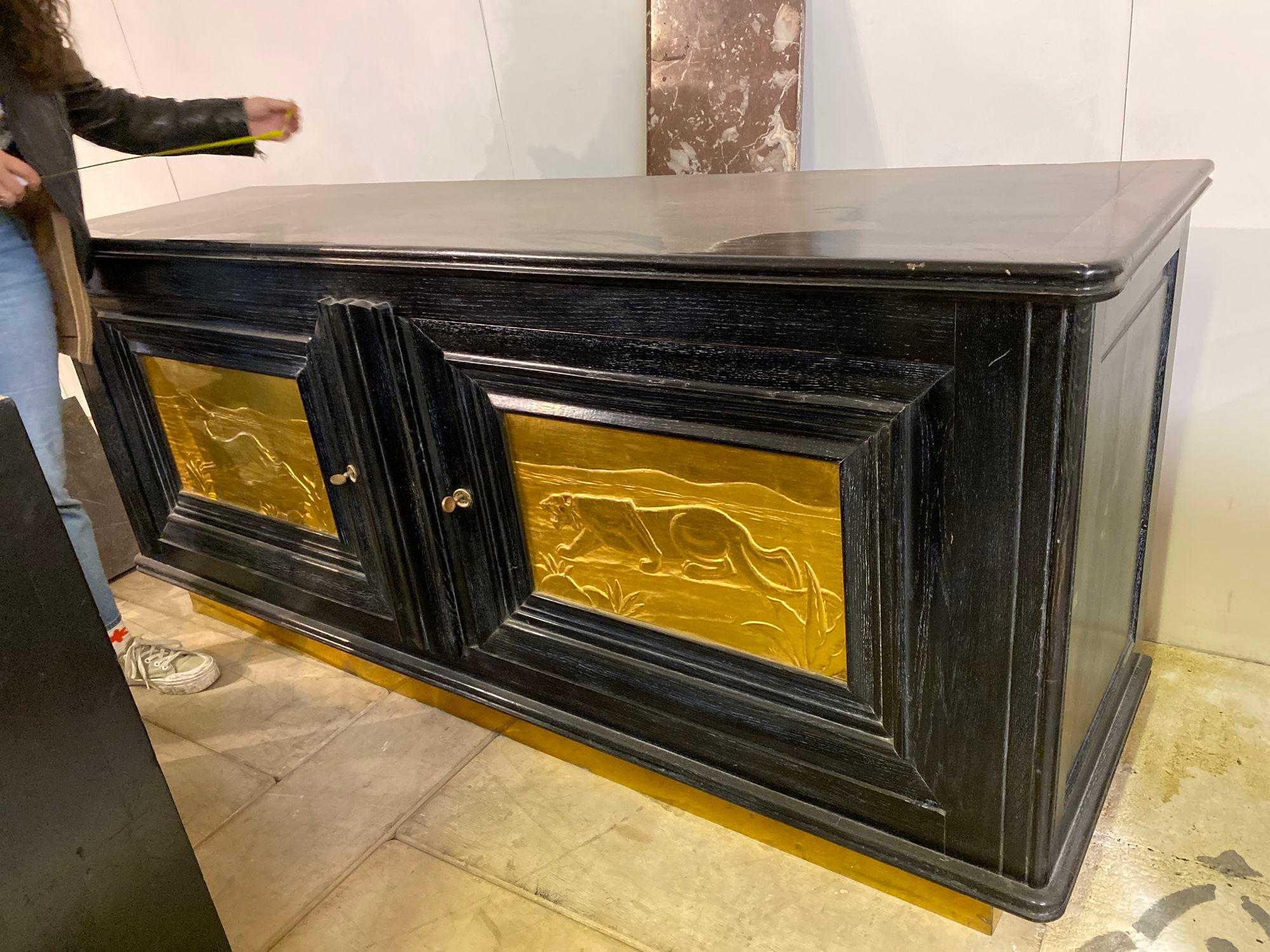 Step into the glamour of 1950s Hollywood Regency with this exquisite sideboard. Its two doors are adorned with a captivating gilt front depicting a hunting scene, where a majestic lion and a graceful impala meet in a dramatic showdown. The black