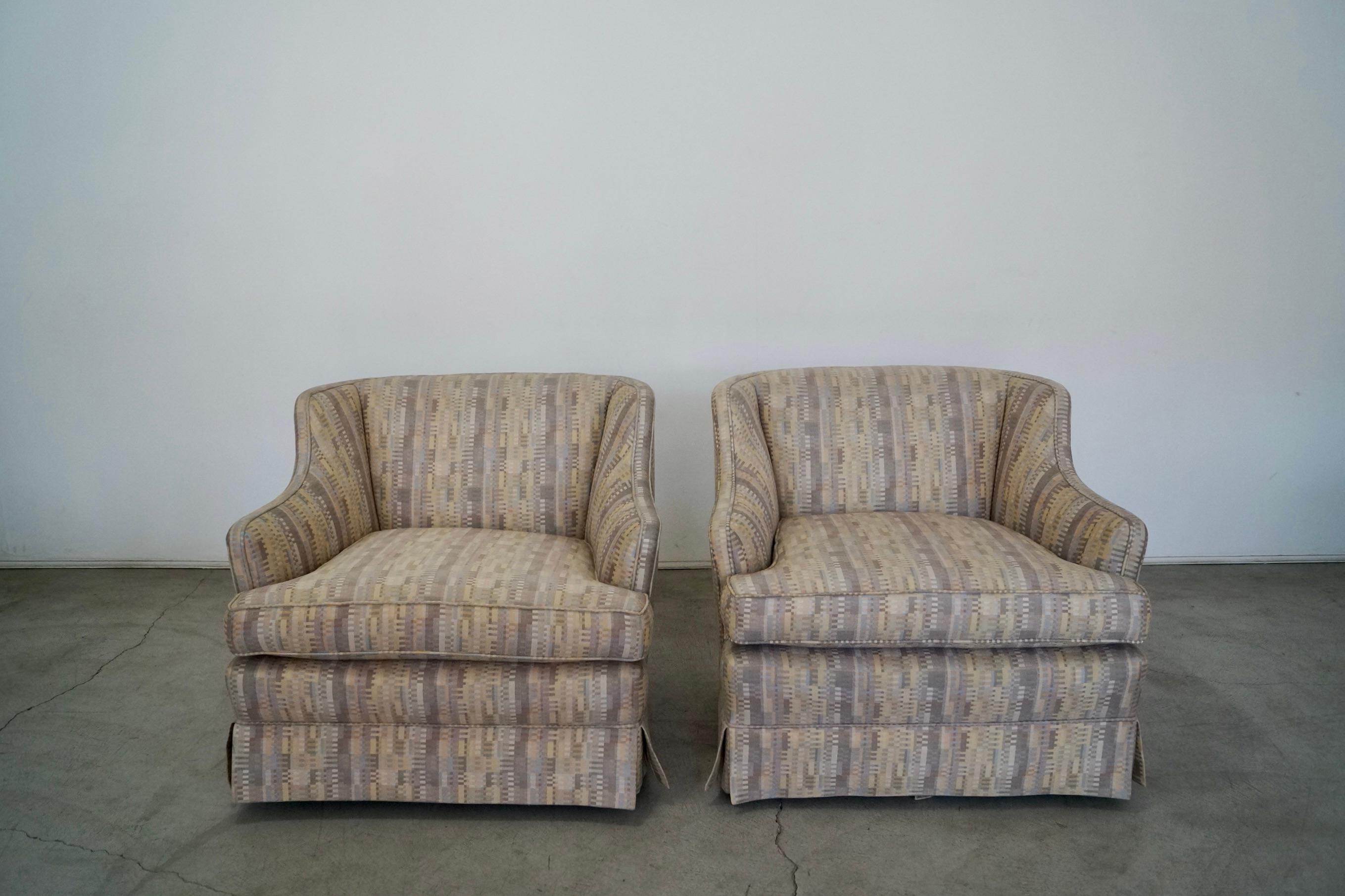 Vintage 1950's pair of lounge chairs for sale. This pair was reupholstered a while back, and is in excellent condition. The fabric has a geometric pattern in muted colors. It has a variation of colors in purple, yellow, blue, white, and gray. These