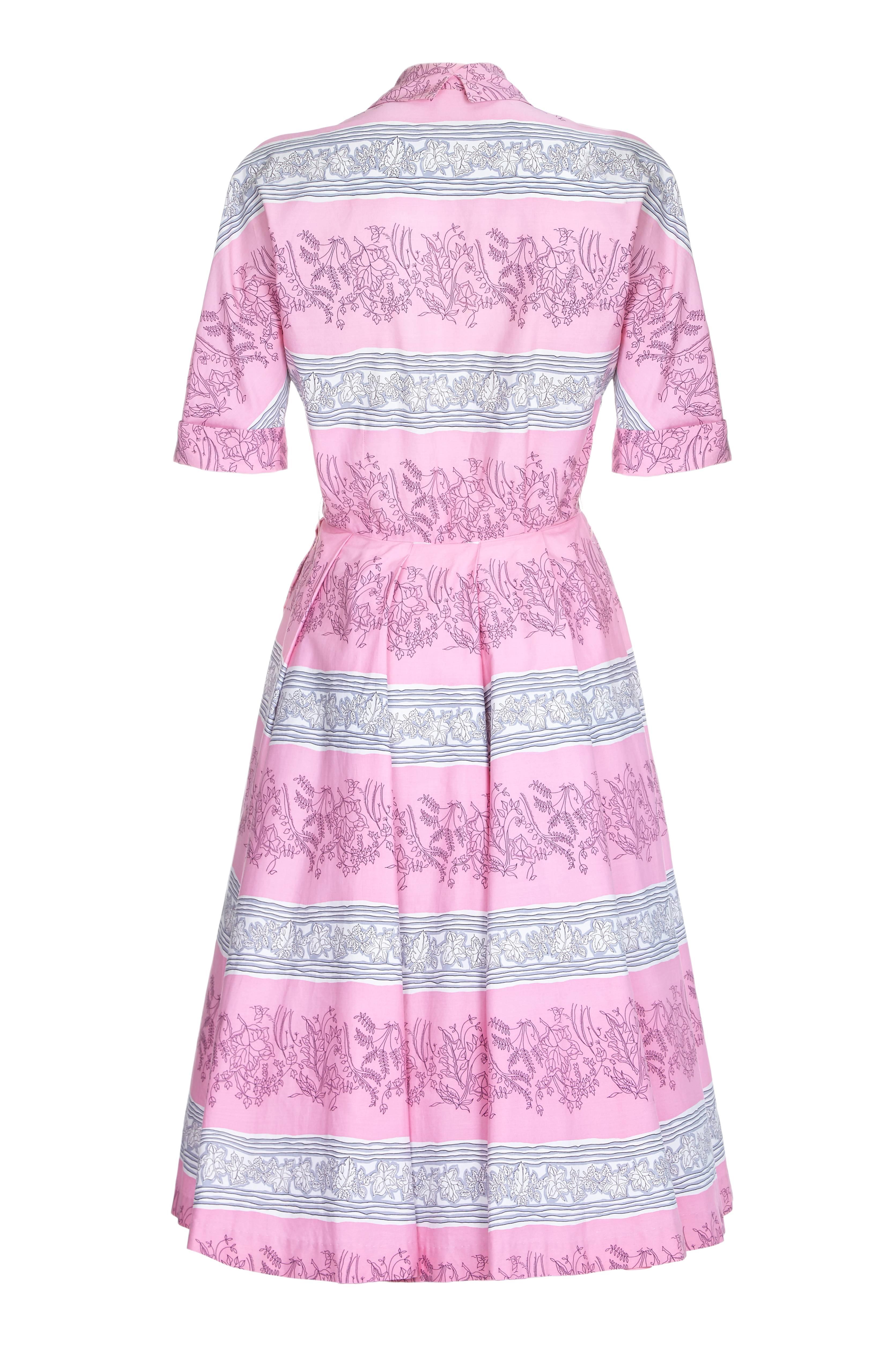 Dieses knackige Baumwollkleid wurde von Horrockses in den 1950er Jahren entworfen. Der Druck in Bonbonrosa, Grau und Weiß ist atemberaubend; eine Auswahl an Blättern ist über den Druck verstreut, darunter mehrere Efeuarten. Die Silhouette ist