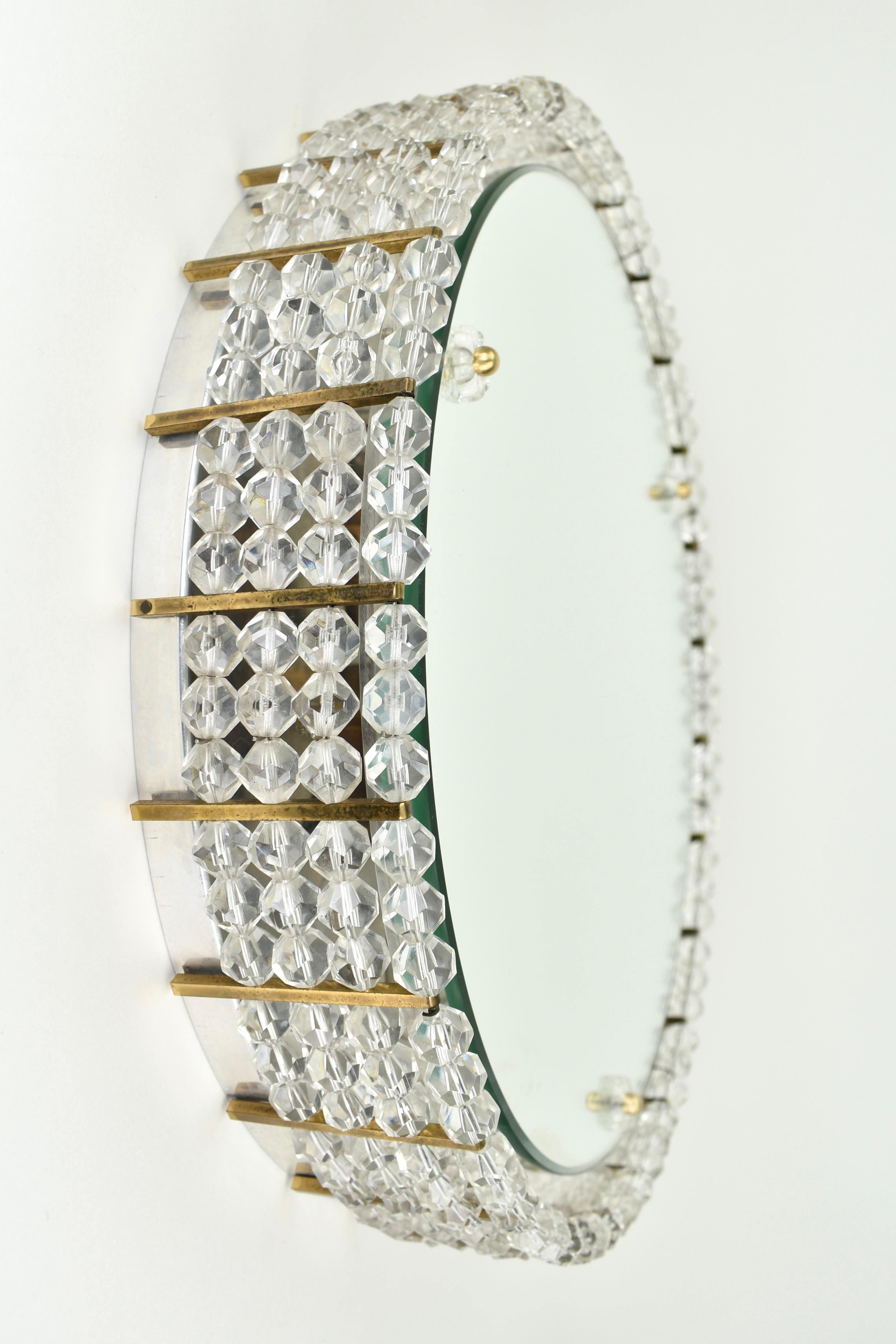Superbe miroir des années 1950 de l'entreprise/designer autrichien Rupert Nikoll. Le miroir peut être éclairé, ce qui donne un bel effet à travers les perles de laiton et d'acrylique qui l'entourent. En très bon état, entièrement d'origine. Le