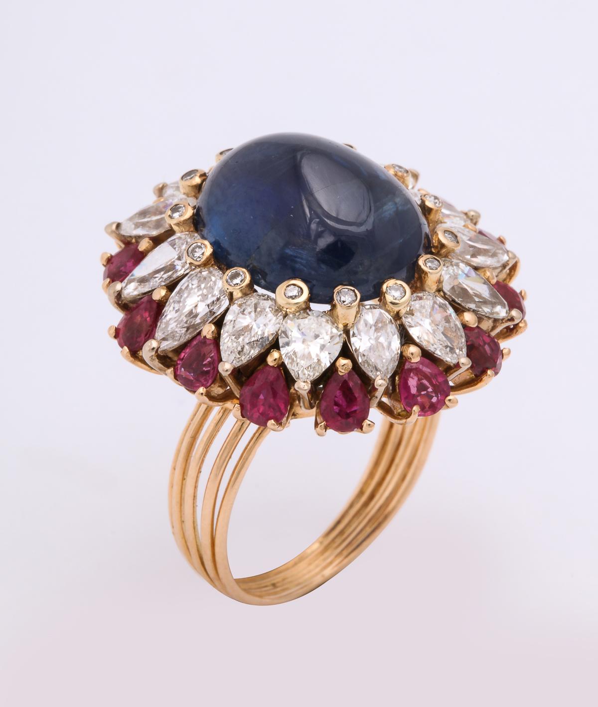 One Ladies 18kt Yellow Gold Cocktail Ring Centering A Deep Blue Cabochon Sapphire Weighing Approximately 14 Carats. Ring Is Surrounded By Fourteen Pear Shaped Diamonds Weighing Approximately Three Carats. This Cocktail Ring Is Further Embellished