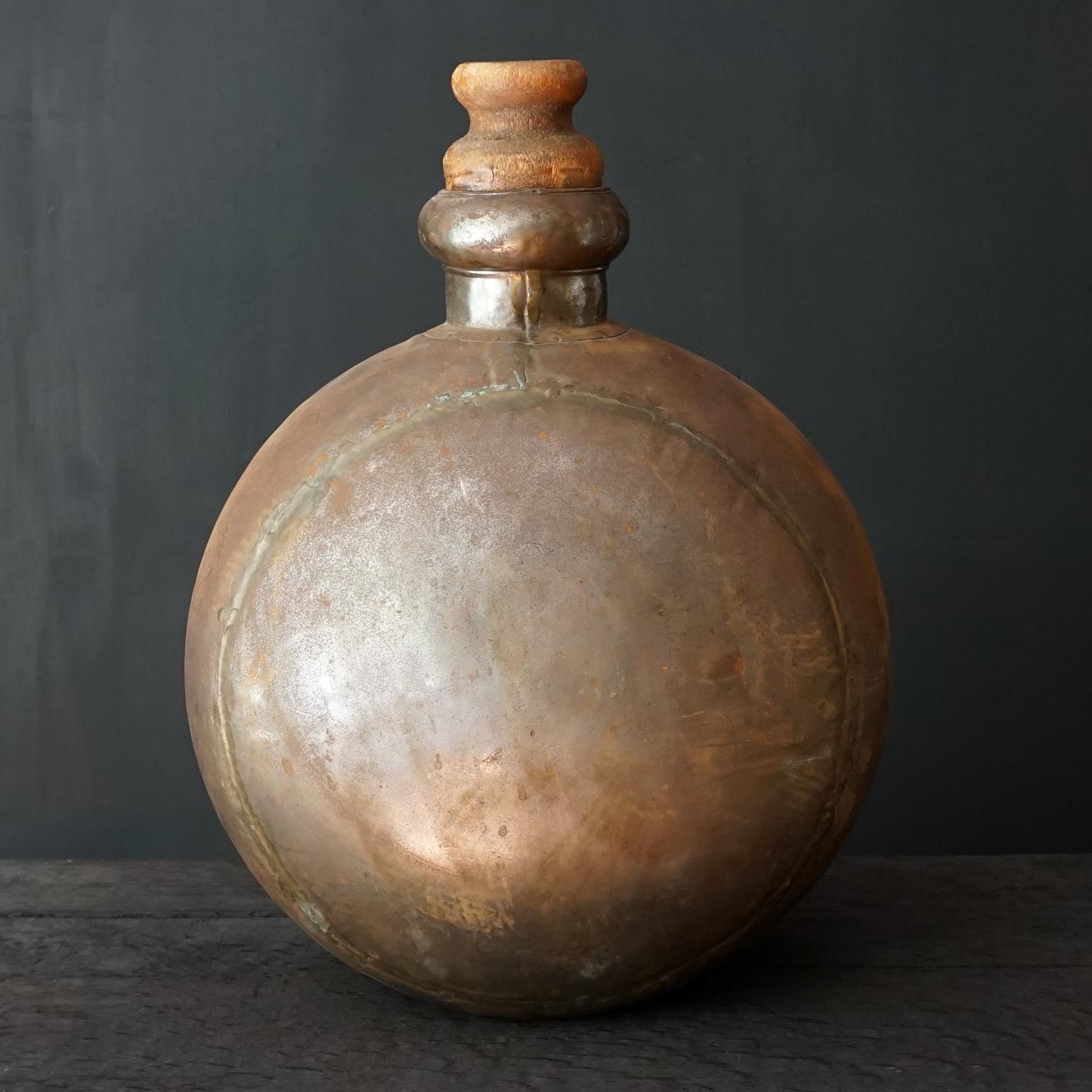 Beautiful decorative large vintage Indian craftsmanship hand-hammered metal water jug with wooden cork from the mid 20th century. This metal bulbous iron bottle has a great 'antique' finish due to age and use. 
Great for decoration in any kind of