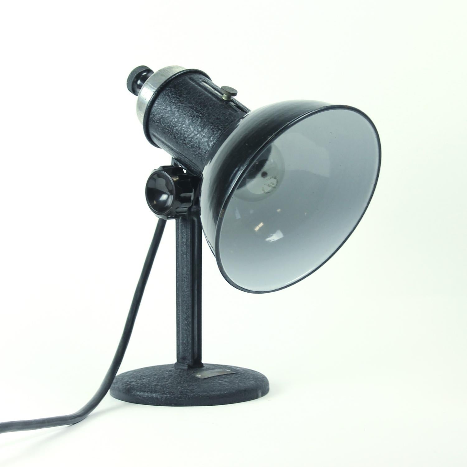 This interesting table lamp will always catch your eye. It is made of black metal, but the simple design makes it look very elegant. Made entirely of metal. Shield adjustable. In an excellent condition. Works on one bulb, European plug.