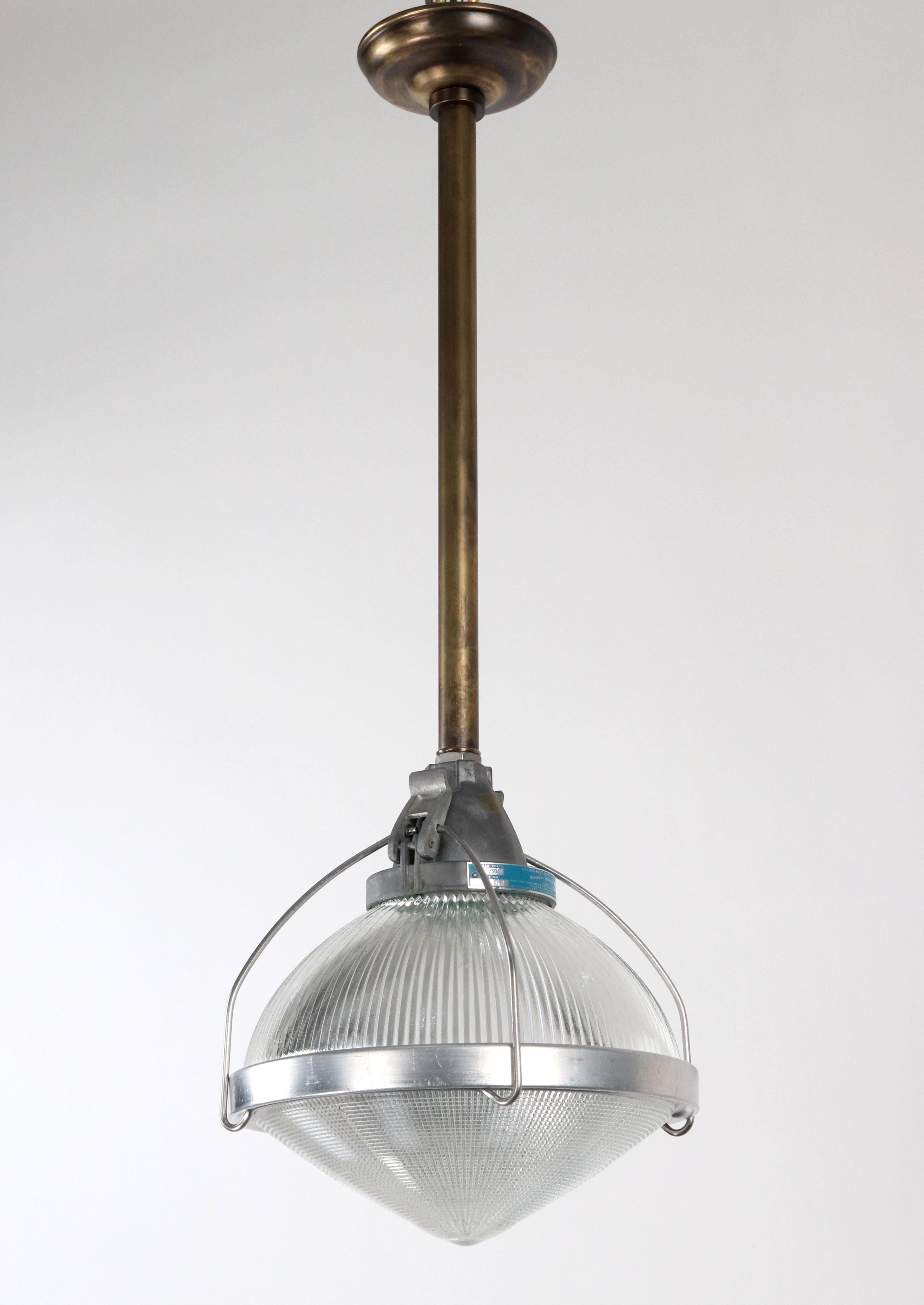 1950s industrial pendant light with a clear pointed bottom Holophane glass shade, a brushed steel band, and an antique brass pole. This requires one standard Edison style medium base bulb. Good condition with appropriate wear from age. The price