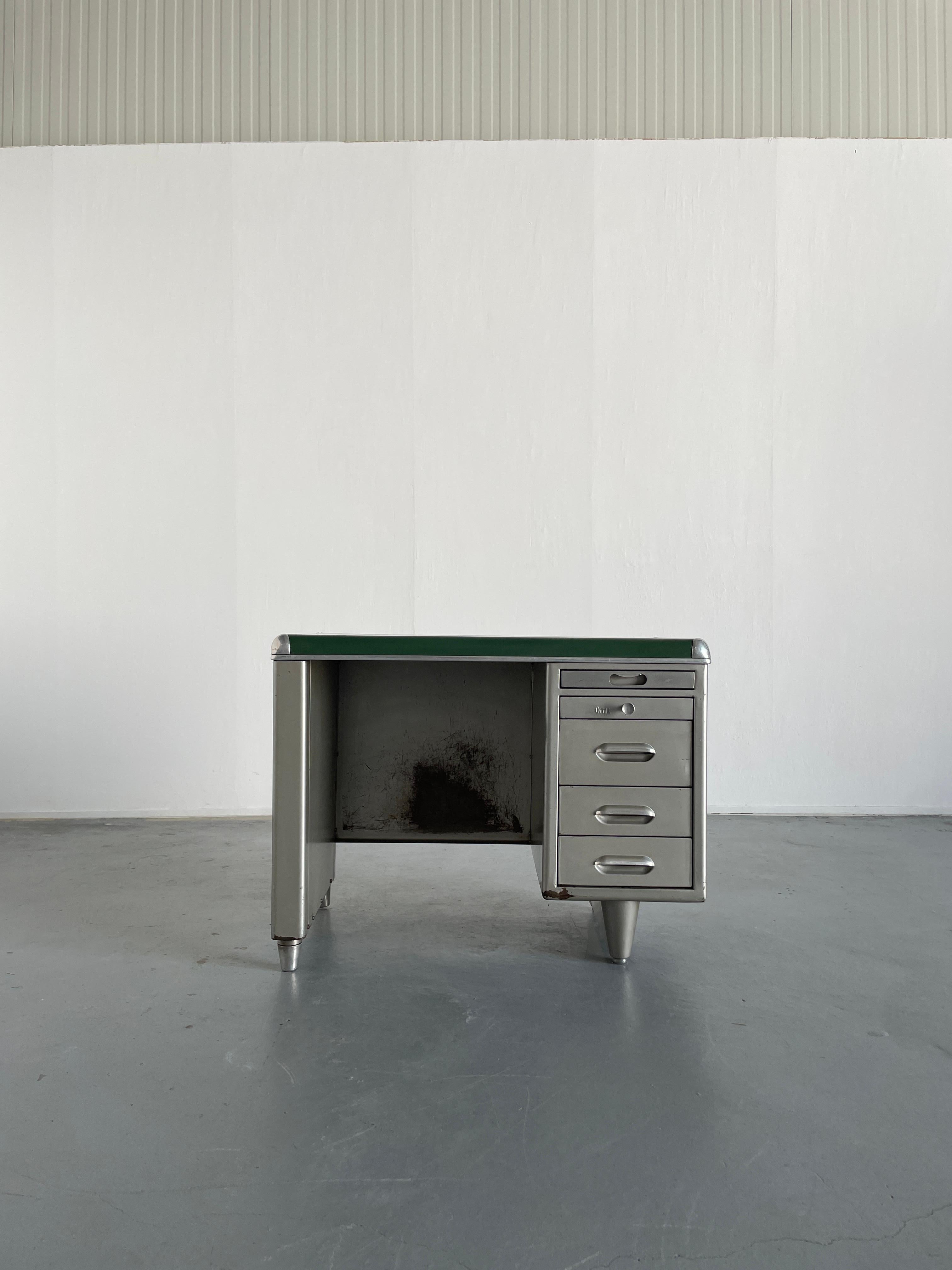 A unique small 1950s industrial design single bank steel tanker desk with green top, produced by Orma Milano from Italy.
Features four drawers of different sizes, and a fifth top drawer that can be used as an additional working space.
Labeled.

In