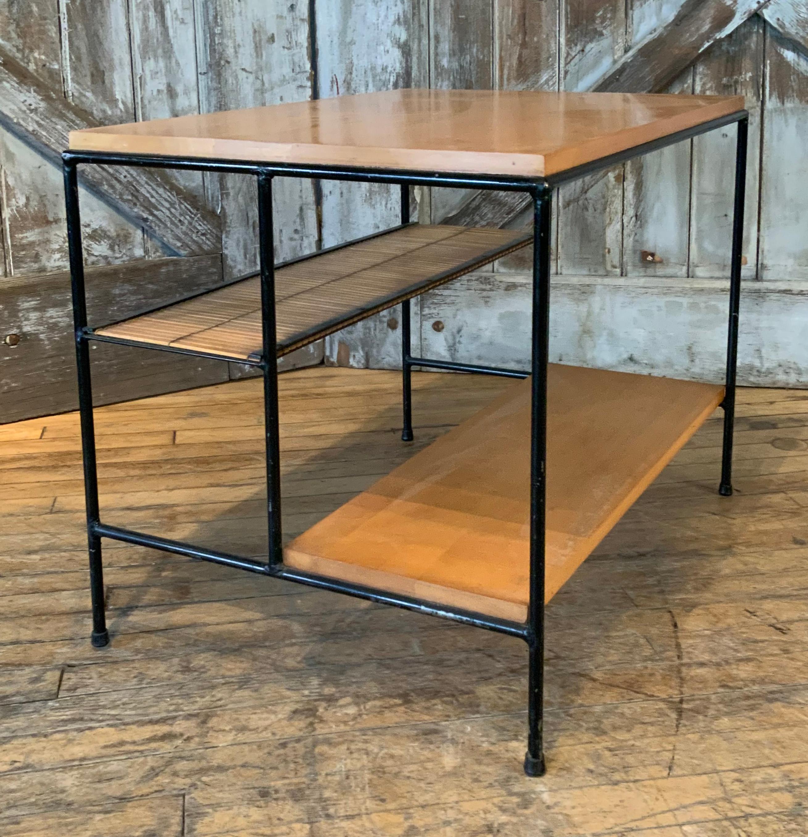 A very handsome 1950s table or nightstand by Paul McCobb, from the Planner Group series for Winchendon, with wrought iron frame in original black finish, birch top and lower shelf, and woven rattan mat middle shelf. in good condition overall with