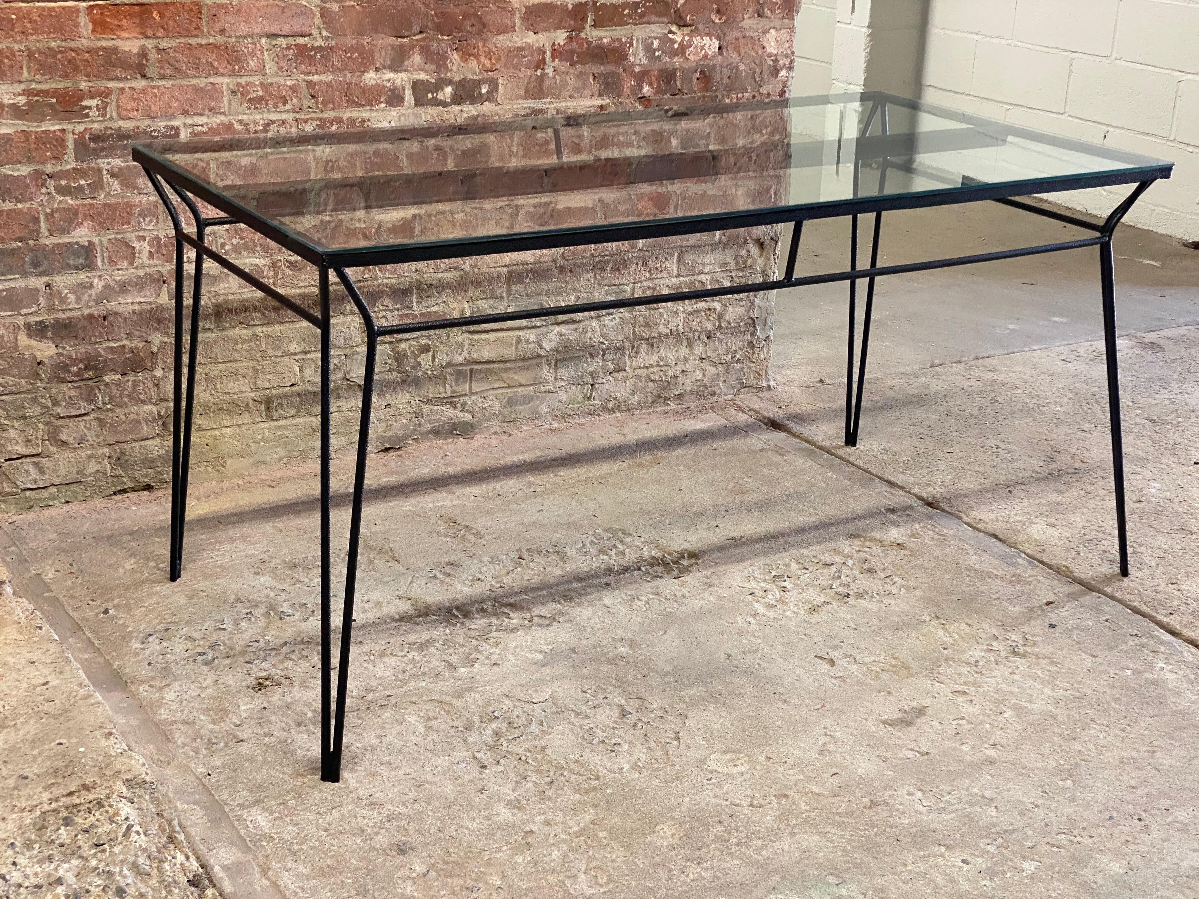 Rectangular iron frame table with a glass top. The table features a center brace for structure and wonderfully tapered and pointed hairpin leg. An unusual decorative aspect that adds a simplistic flair to the design.

Good overall condition. All