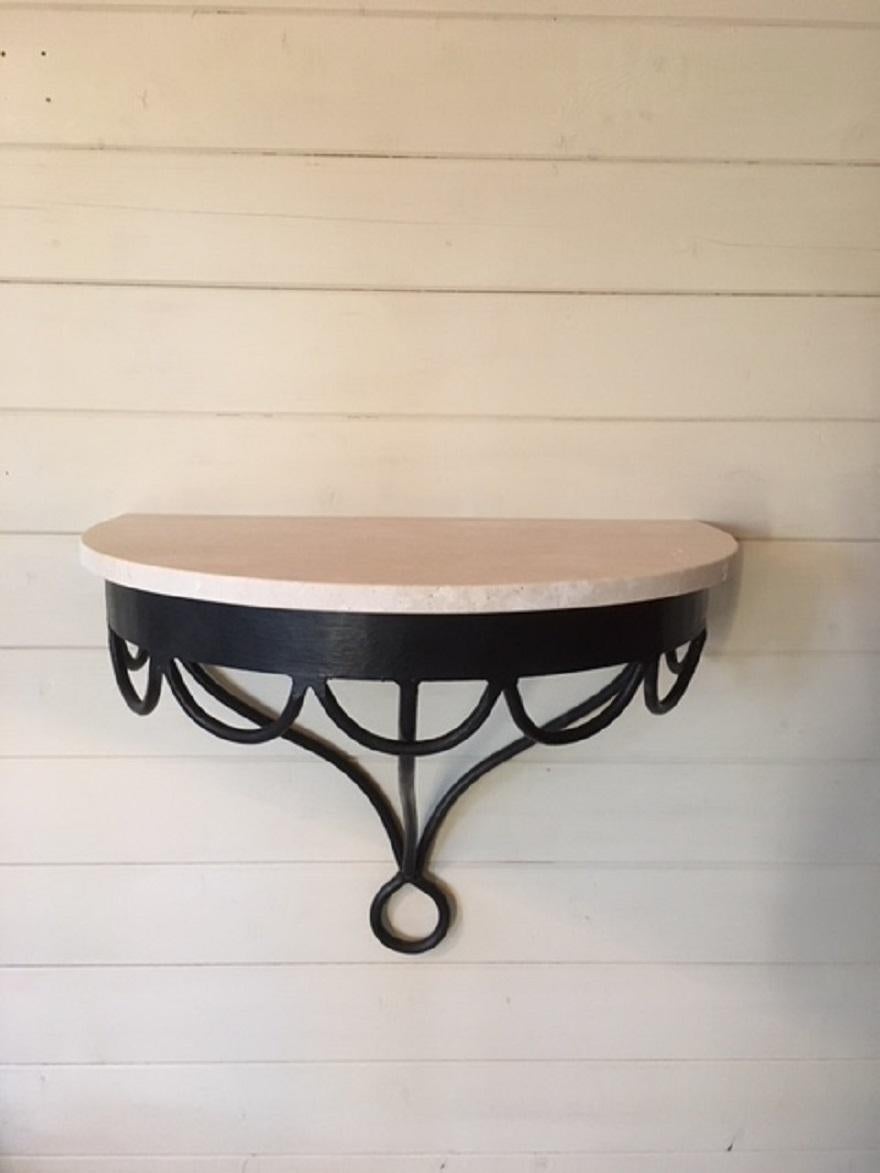 A French black painted wrought iron and unfilled travertine stone (replaced) top small demilune wall console.