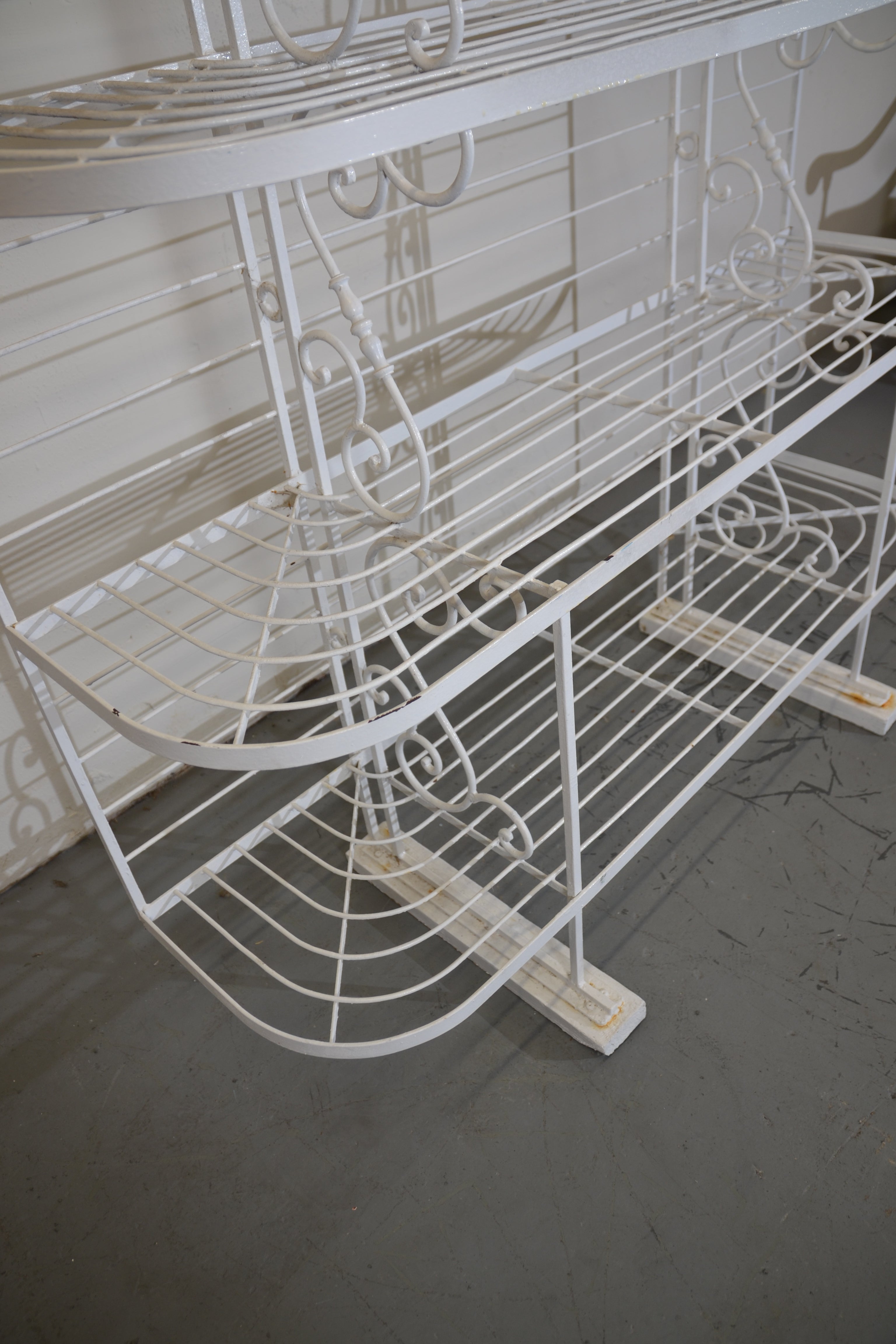 1950s  iron French baker's rack. A small shelve on each side and three large shelves on the bottom. The iron feet are standing on wood.