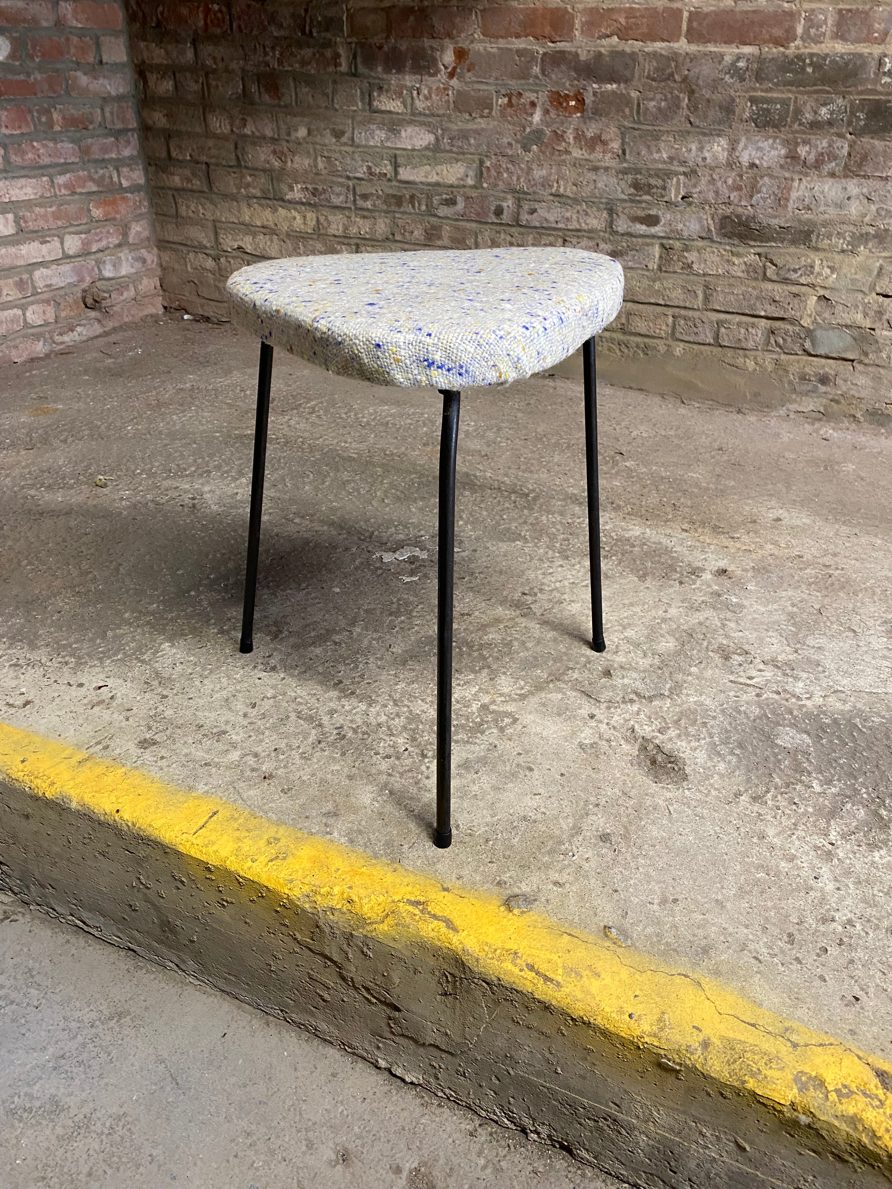 Iron tripod stool with guitar pick shaped seat. A wonderful 1950s accent piece. Graceful and refined design. Good overall condition with period fabric upholstery. Structurally sound and sturdy. All welds are intact. Fresh new fabric. Wear consistent