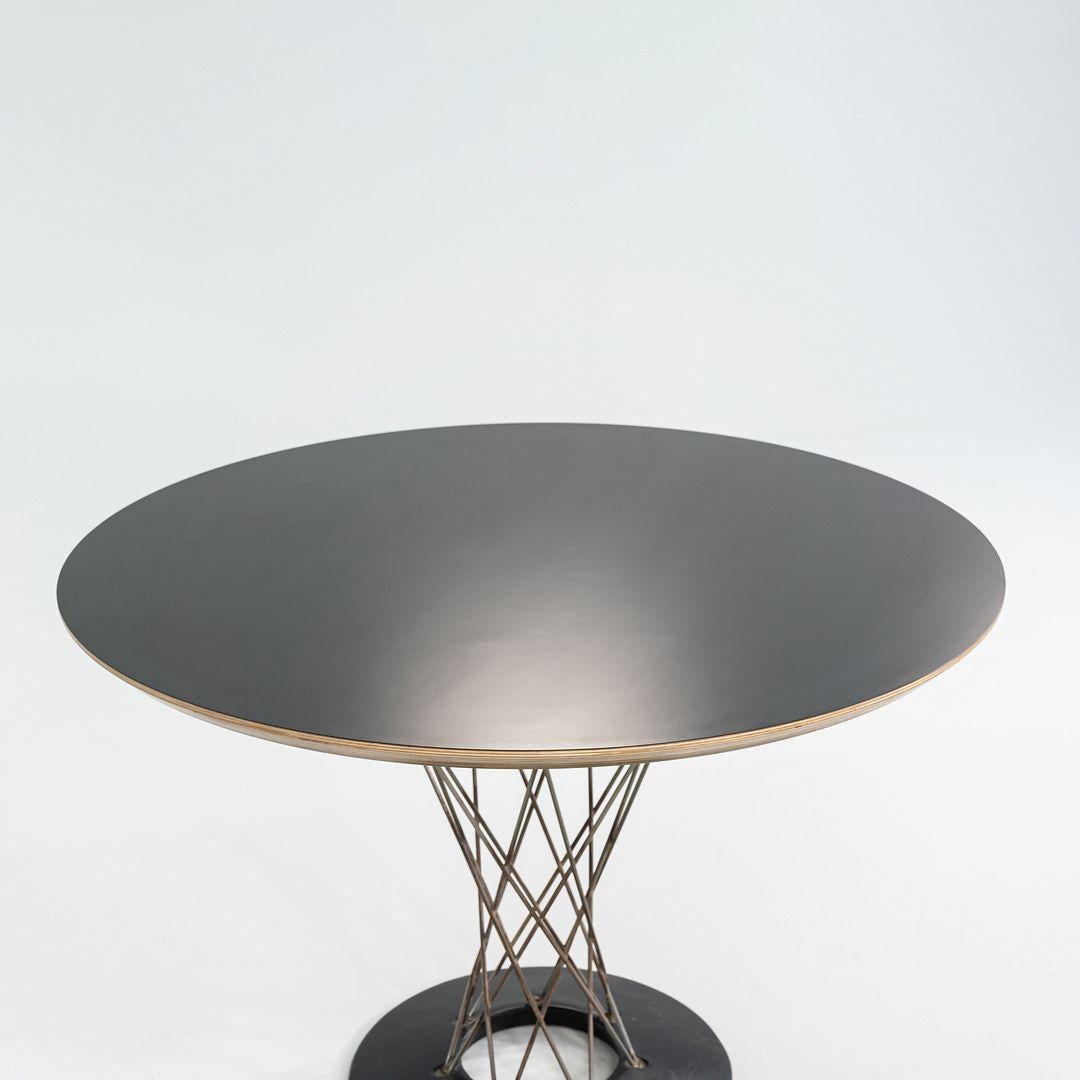 Il s'agit d'une table à manger Cyclone, modèle 311, initialement conçue par Isamu Noguchi pour Knoll en 1957. Cet exemple date des années 1950. La pièce est composée d'une base en fonte revêtue d'un émail en porcelaine noire et d'un nouveau plateau