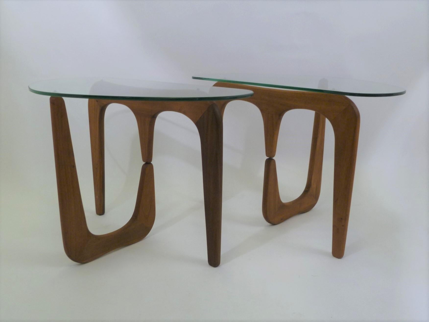 Organic modern side tables with floating glass tops have inspiration from Isamu Noguchi with their amoeba D-shaped tops over walnut carved bases. Newly replaced glass tops, the bases are beautiful figured walnut in a stylized whale bone form. When