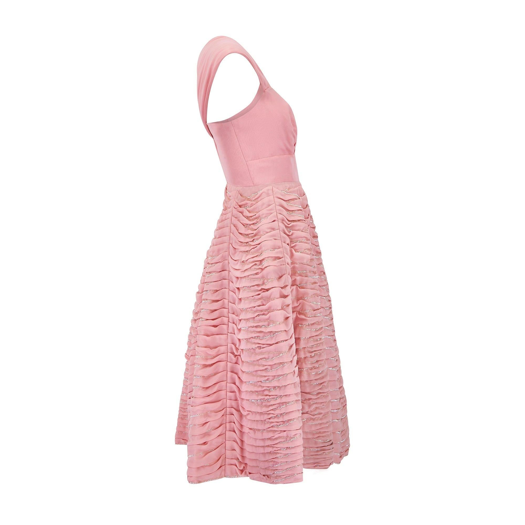This bubble-gum pink gown is Italian couture, known as 'Alta Moda' and was made in the early 1950s.    Displaying many hallmarks of the era, it showcases a swirling full-skirt, cinched waist and bustier top - all tailored from a high quality pink