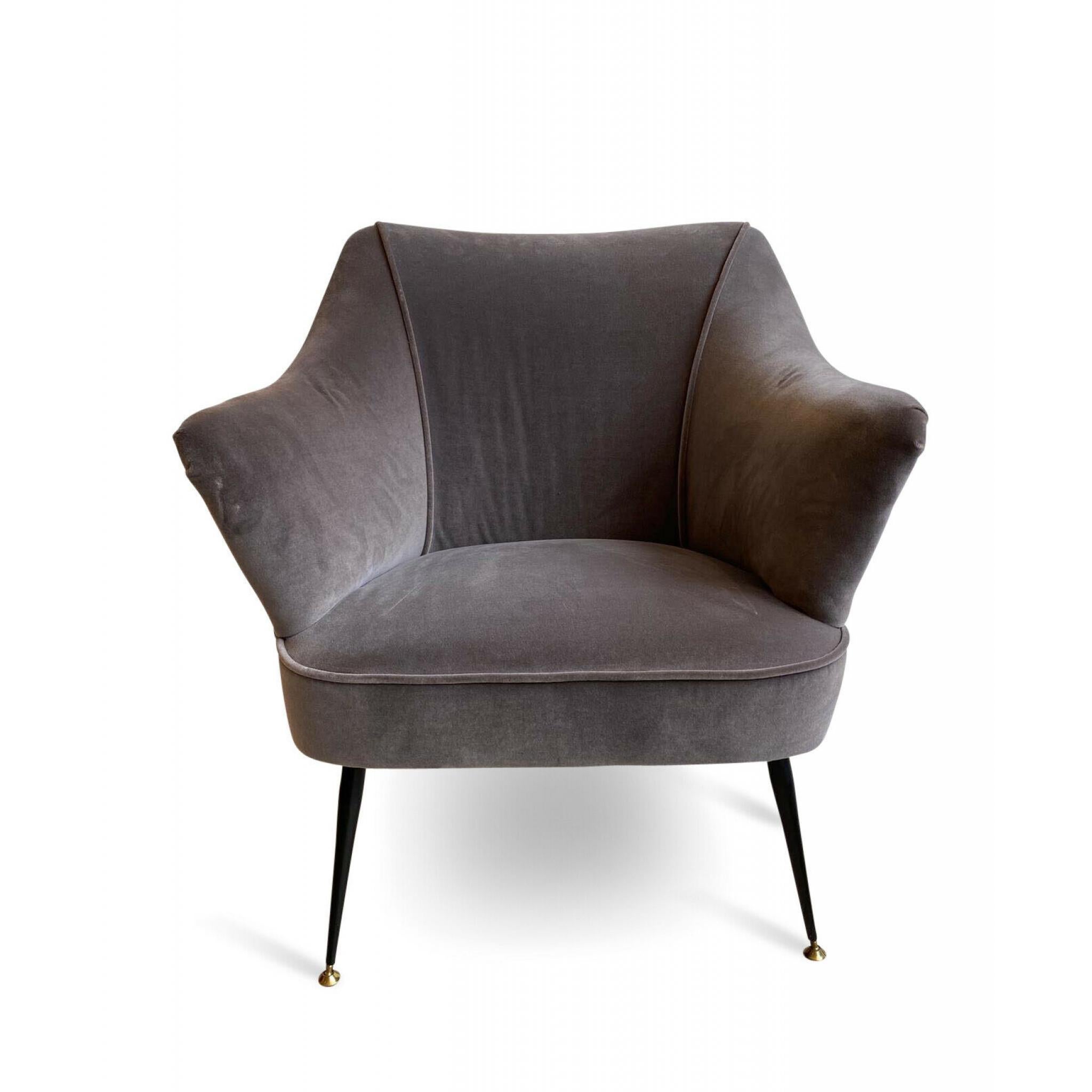 A beautiful and petit 1950s Italian armchair recently reupholstered in a light grey velvet with stud details in the manner of Gio Ponti sat on tall thin black metal legs with brass feet.