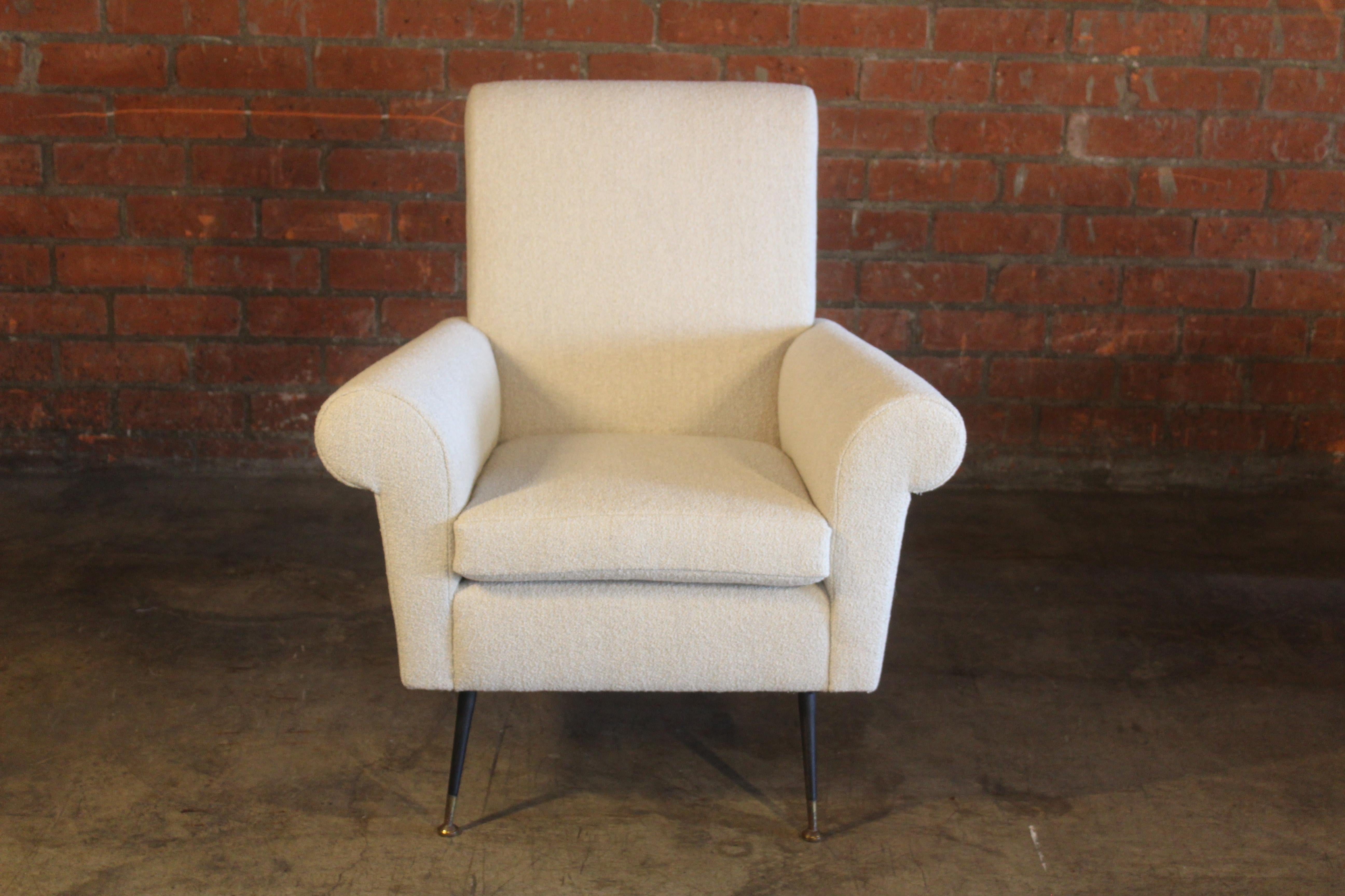 A vintage Italian armchair restored in off white Belgian boucle. Features iron legs with brass sabot feet and glides. In overall excellent condition with patina to the legs.