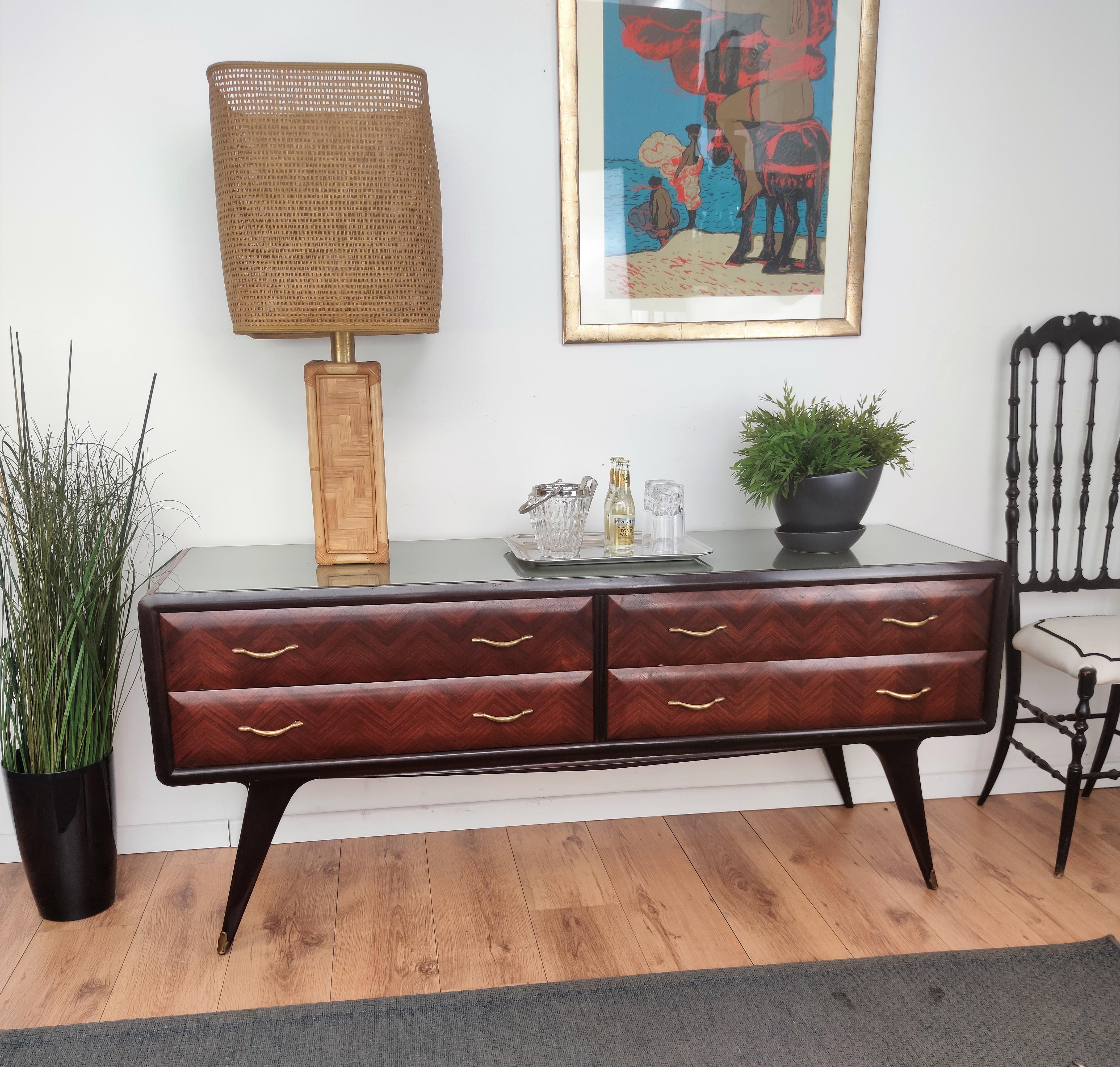 Beautiful Italian 1950s sideboard, credenza, buffet or chest of drawers with elegant and classic wood worked according its natural graining on the 4 drawers frontal drawers with the grey glass top and the final touch details of the original gilt