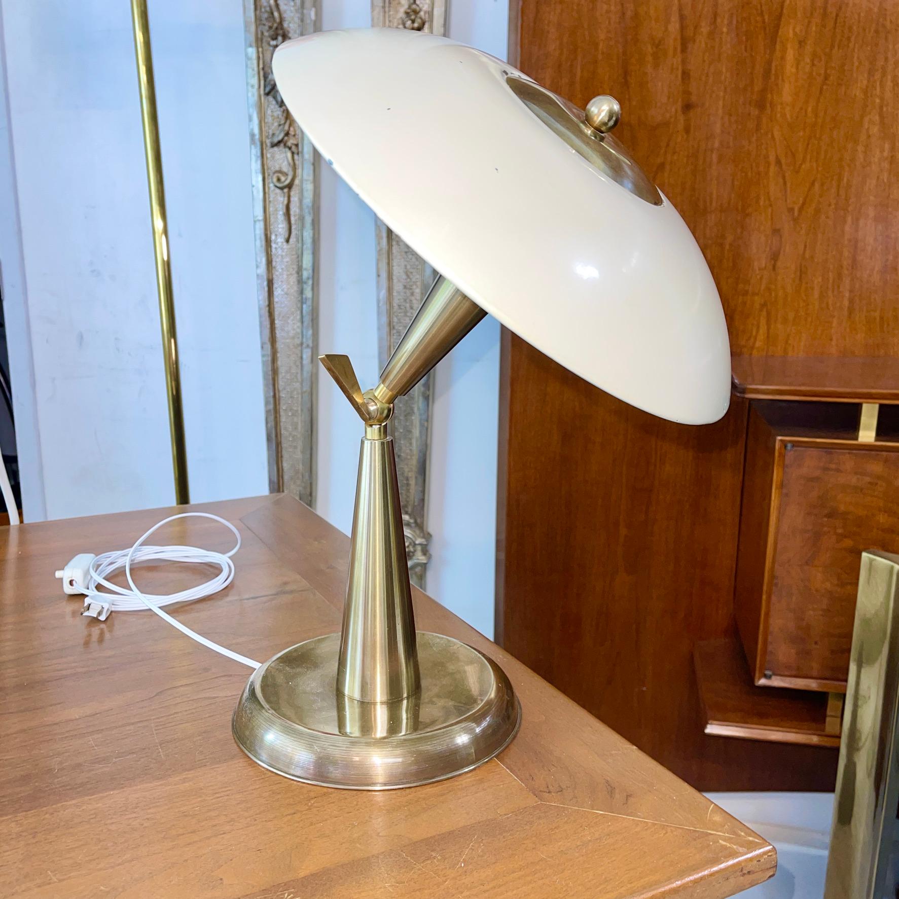 1950's Italian articulating desk lamp made of hefty solid brass and enameled steel reflector. The articulation is controlled by turning the key on the brass ball swivel joint between the double brass cones of the lamp stem. Range of movement is