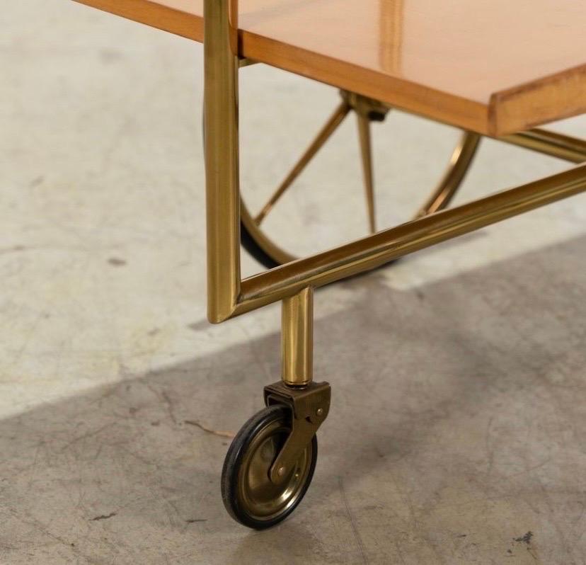 This is a vintage Italian modernist bar cart or tea trolly, presumably designed by Cesare Lacca in the 1950s.

The piece is constructed of lacquered birch, and it has a sculptural brass frame and handle. The brass appears to be solid and not