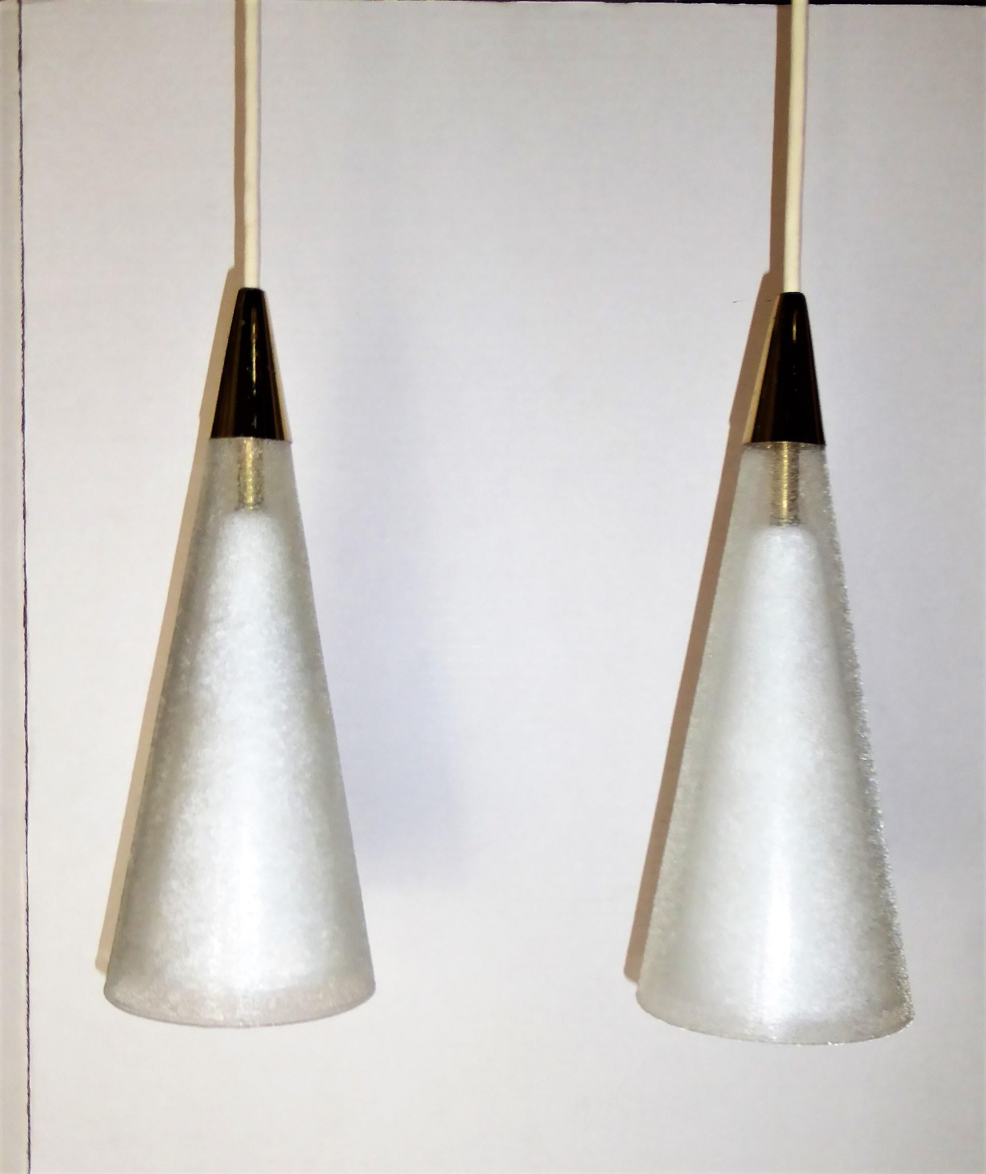 A pair of midcentury Italian pendants of blown glass double cones and brass tips and brass ceiling canopies. Consisting of an inner cone of white milk glass and an outer cone of clear glass with surface glass sugar crystals. Exceptional and luxe.  